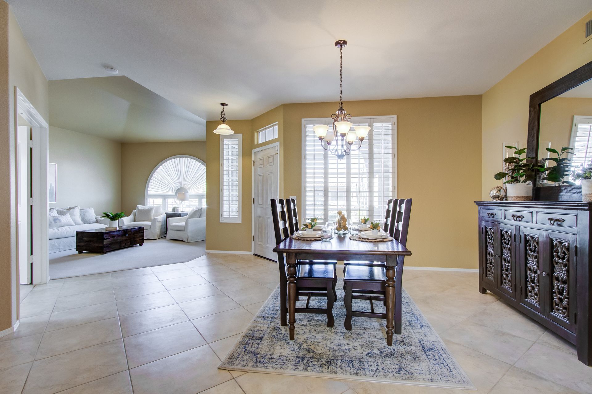 A dining room with a table and chairs and a mirror
