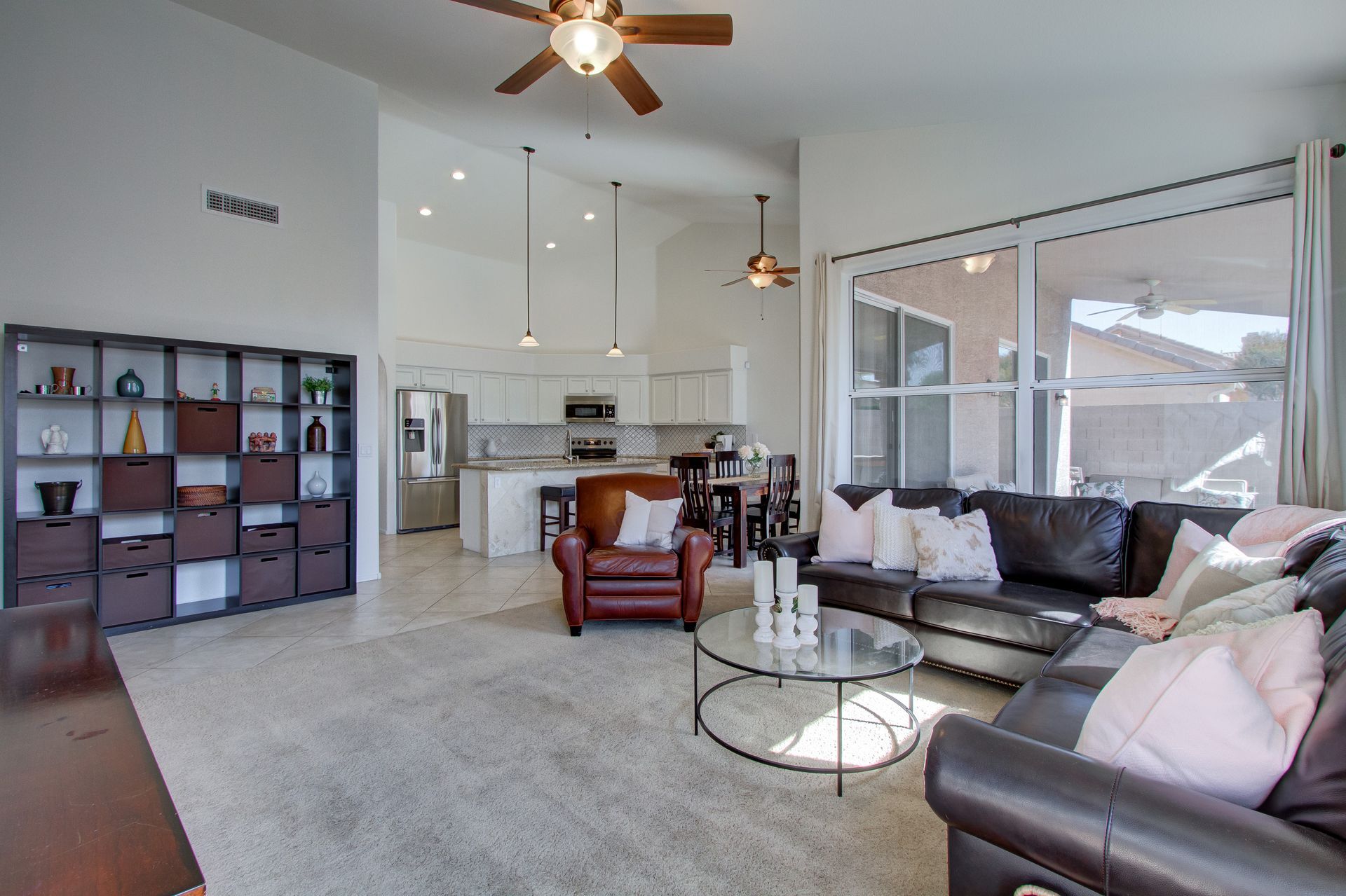 A living room with a couch , chair , coffee table and ceiling fan.