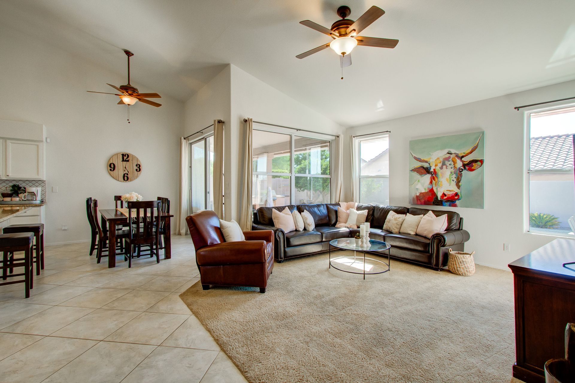 A living room with a couch , chair , table and ceiling fan.