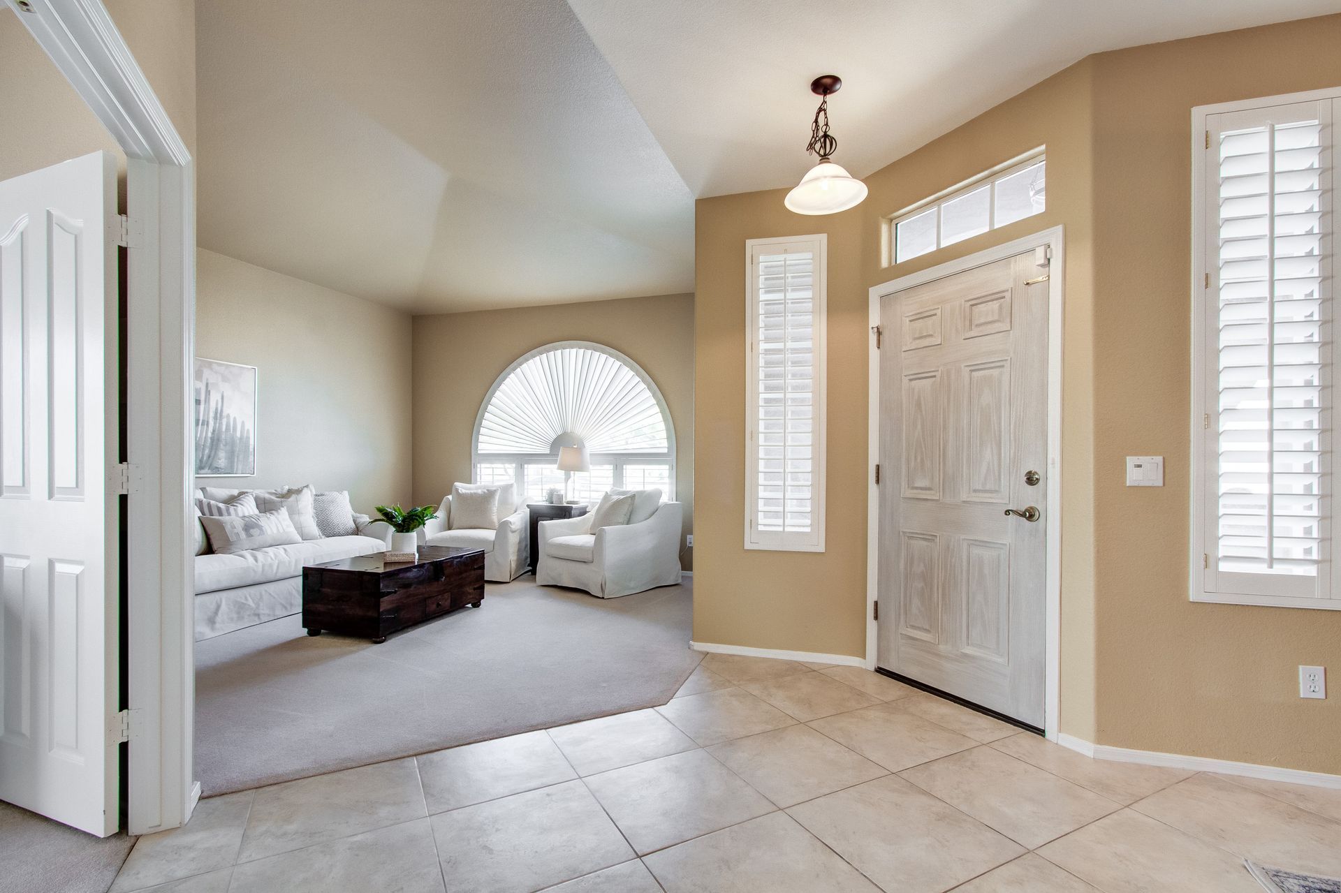 A living room with a couch , chairs , coffee table and shutters.
