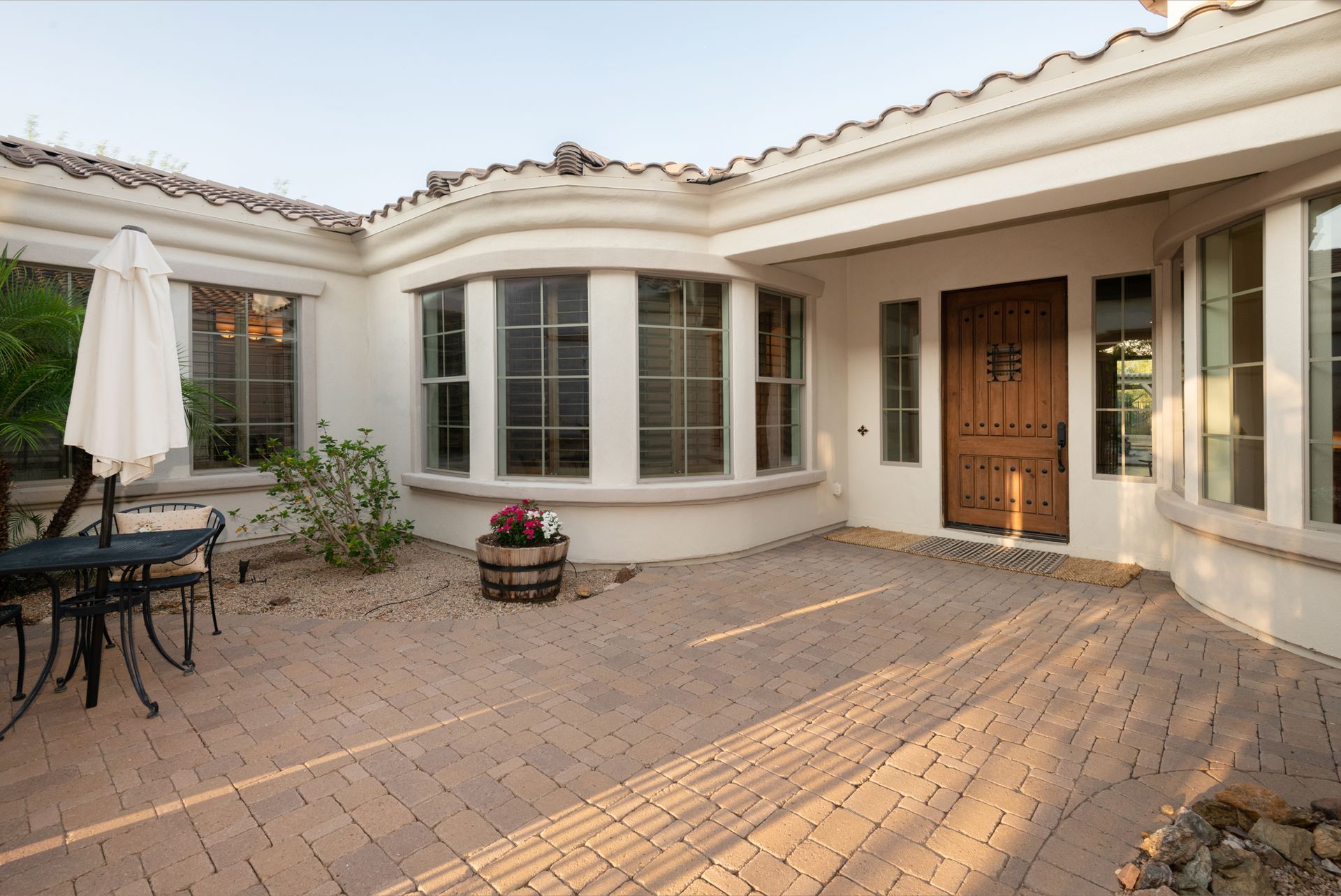 A large white house with a brick patio in front of it.