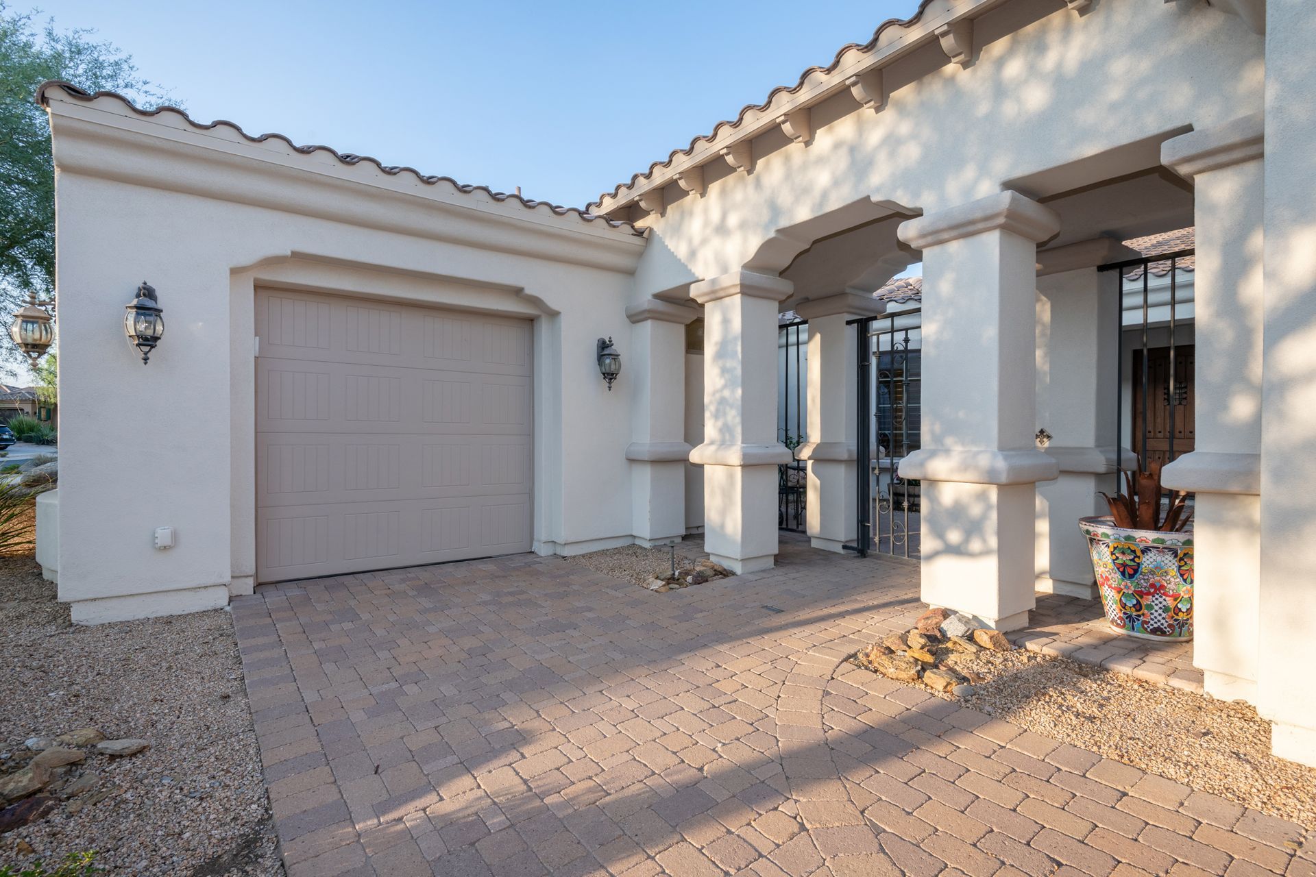 A white house with a garage and a brick driveway.