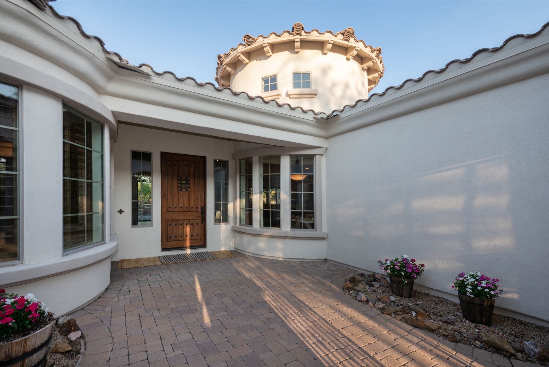 A white house with a wooden door and a circular roof.