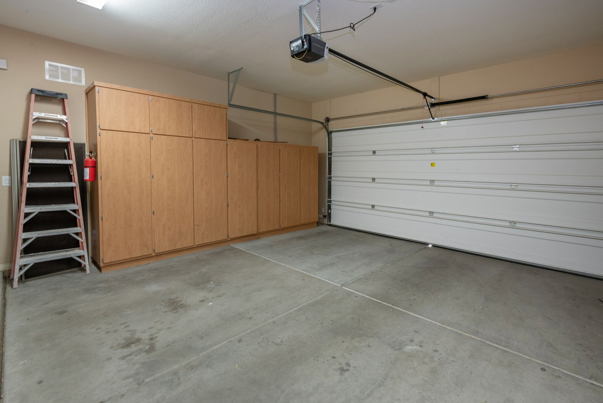 An empty garage with a garage door open and a ladder.