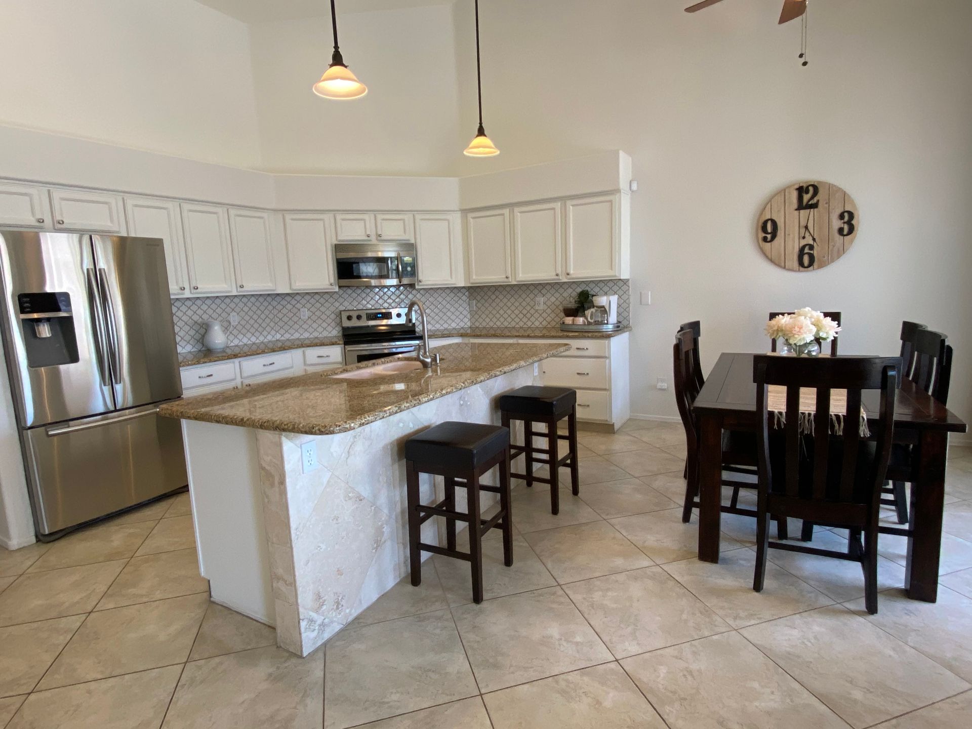 A kitchen with a table and chairs and a clock on the wall