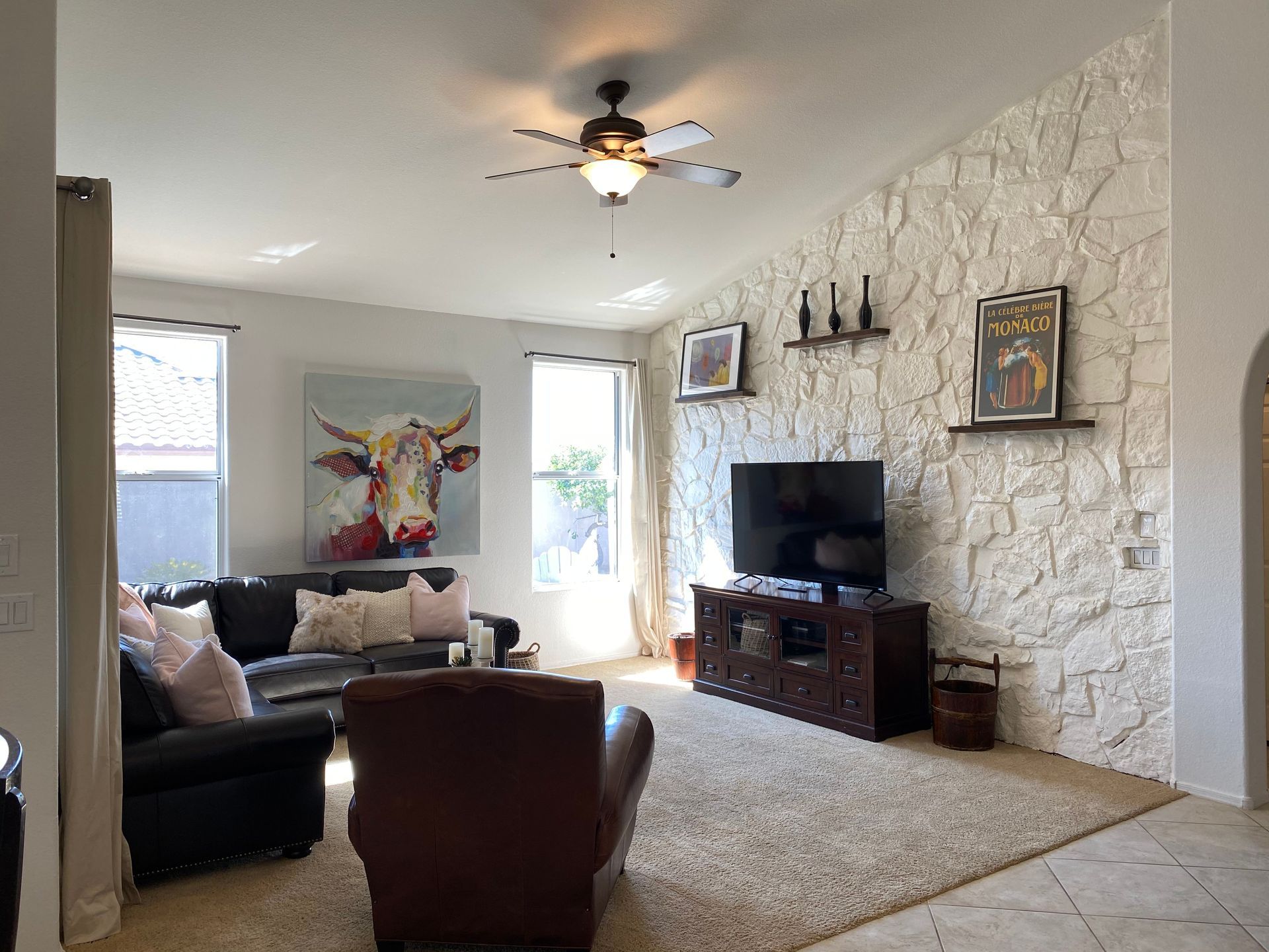 A living room with a cow painting on the wall and a ceiling fan.
