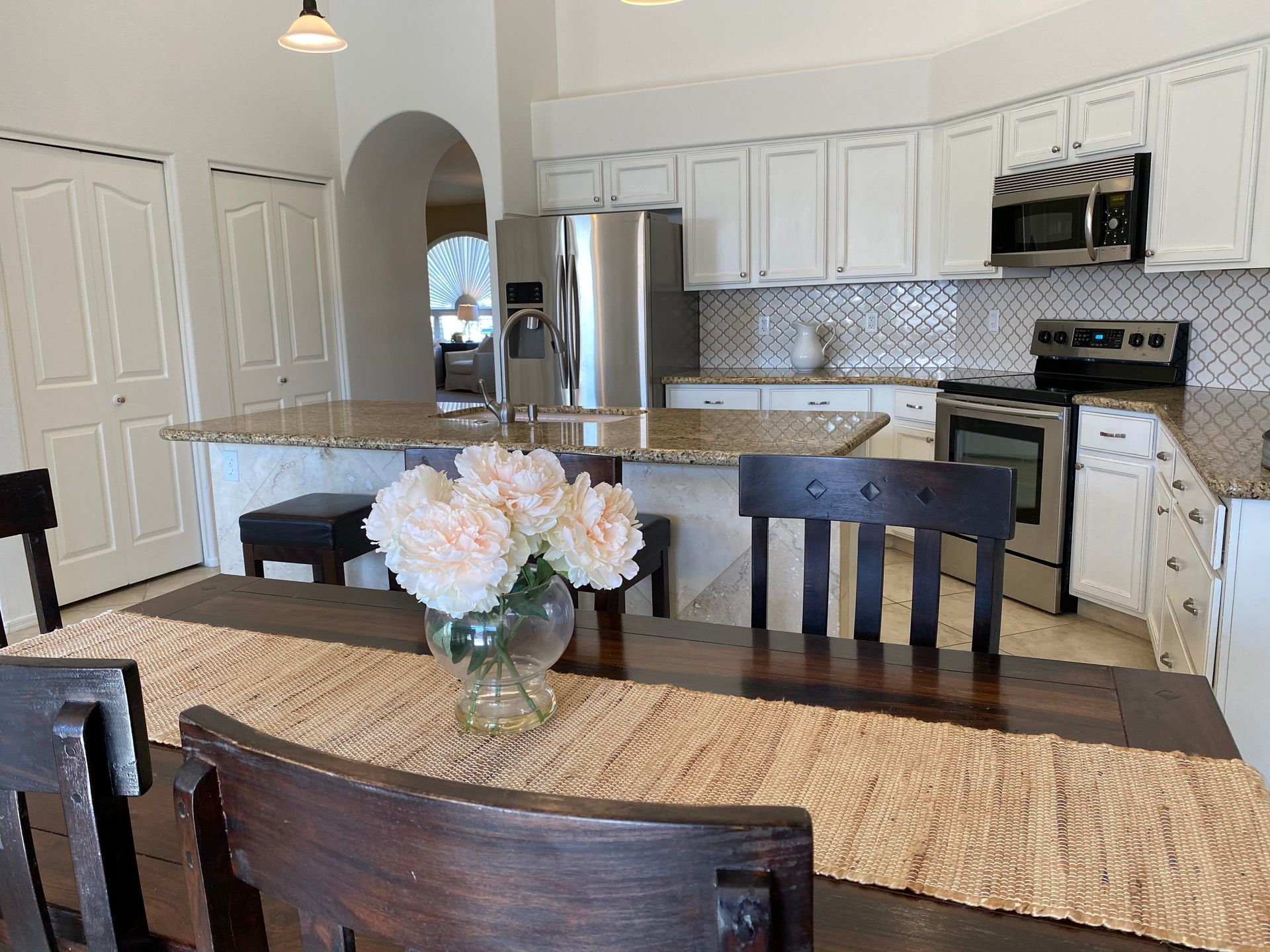 There is a vase of flowers on the table in the kitchen.