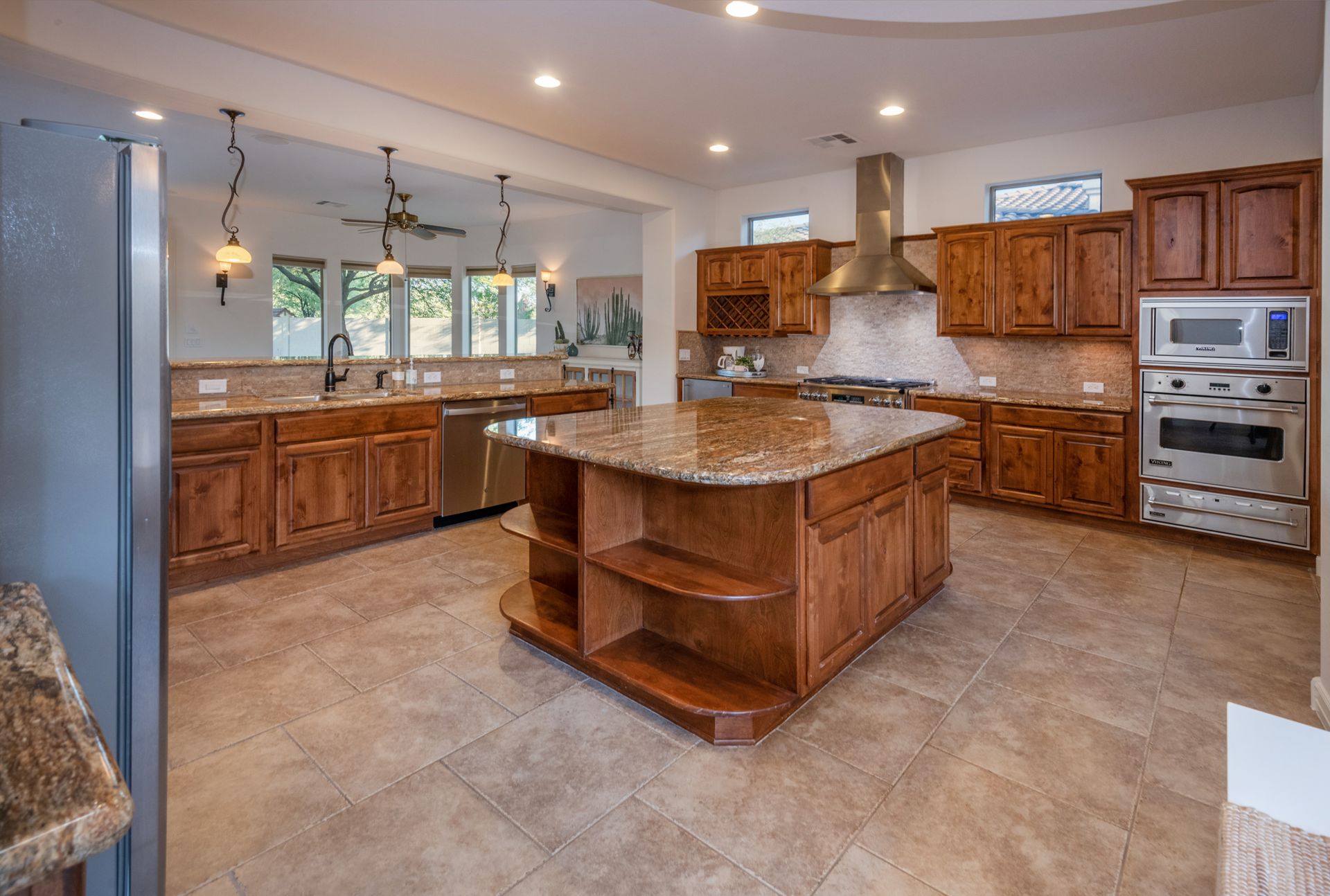 A kitchen with wooden cabinets , granite counter tops , stainless steel appliances and a large island.