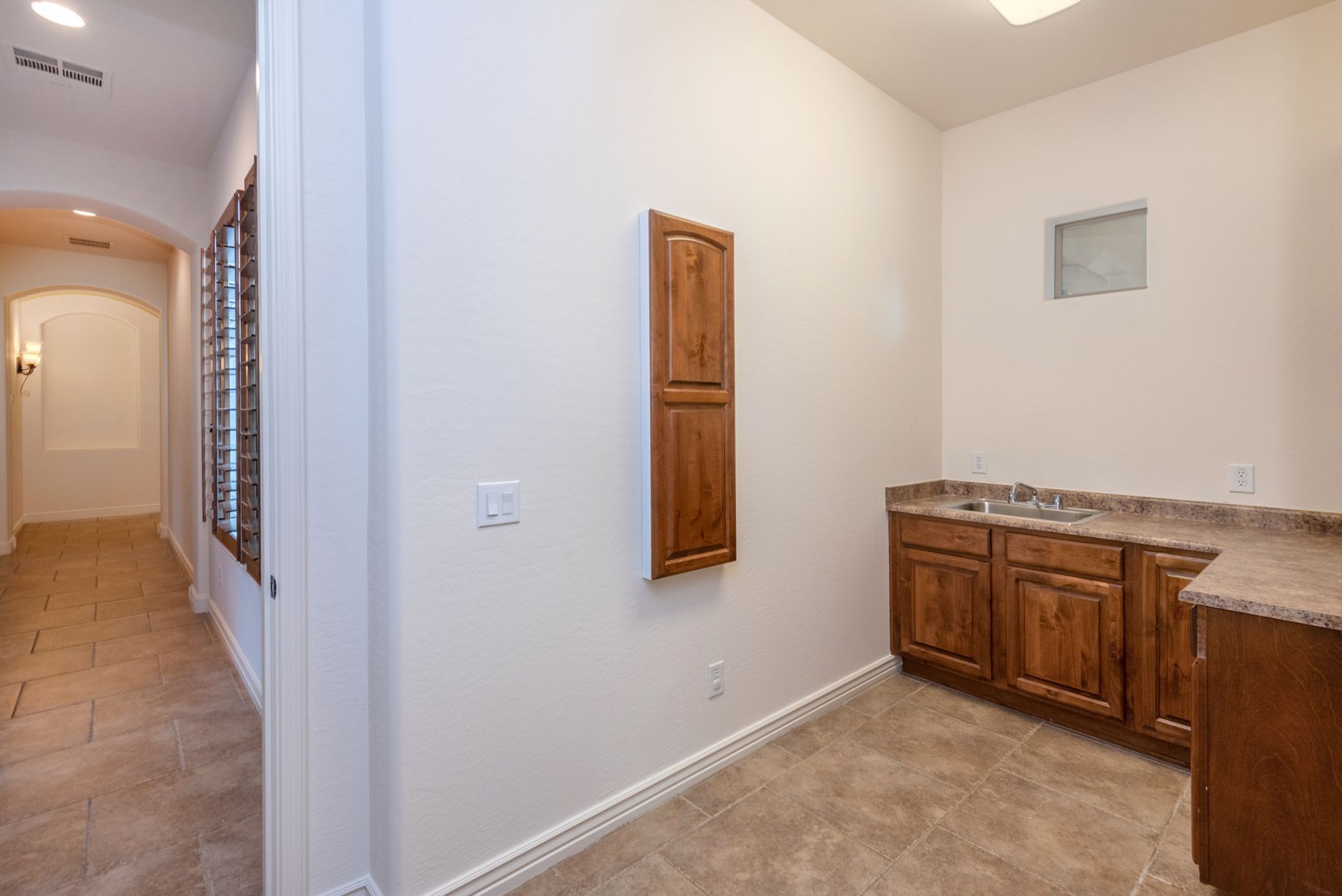 An empty room with a sink and cabinets in a house.