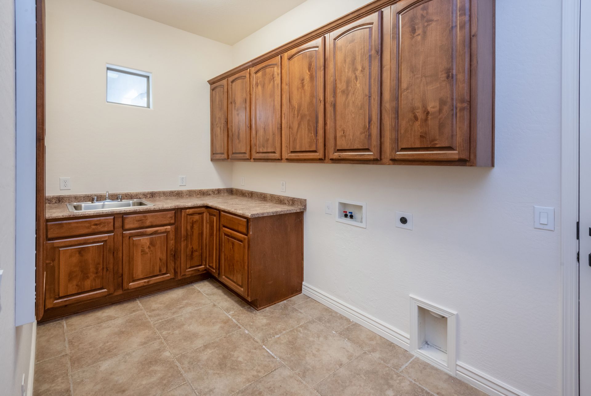 A laundry room with wooden cabinets and a sink.