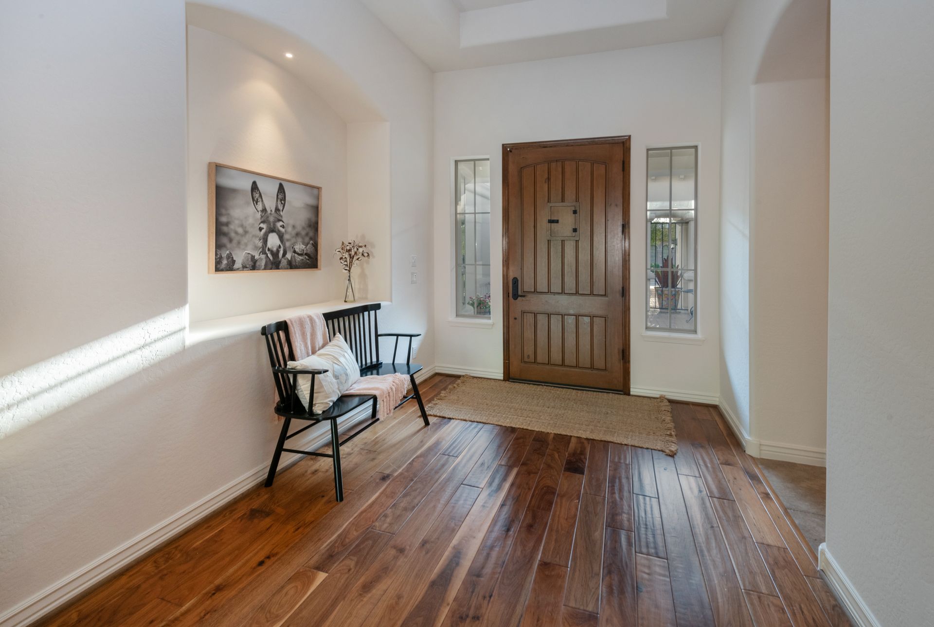 A hallway with hardwood floors and a bench in front of a door.