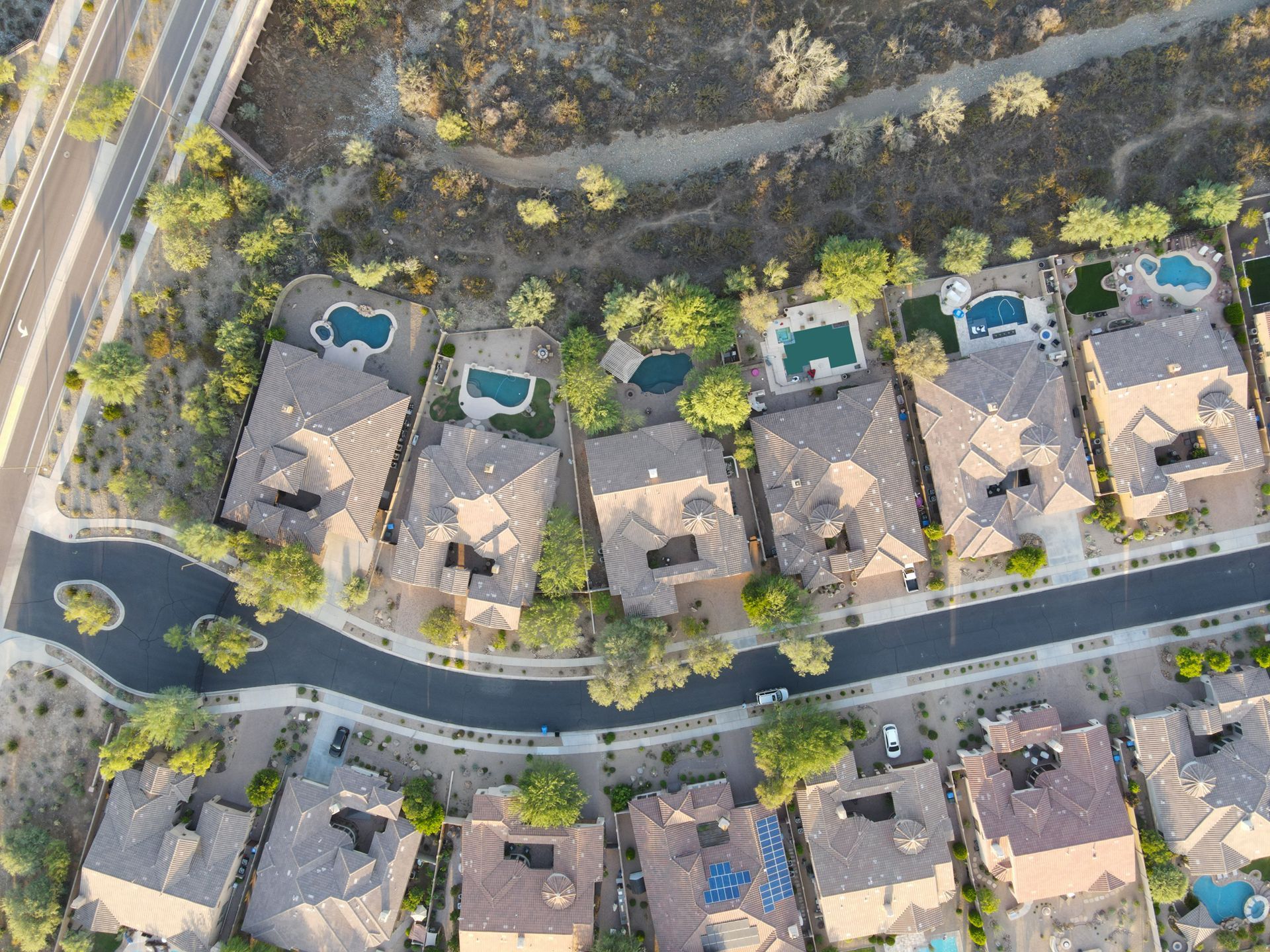 An aerial view of a residential area with lots of houses and pools