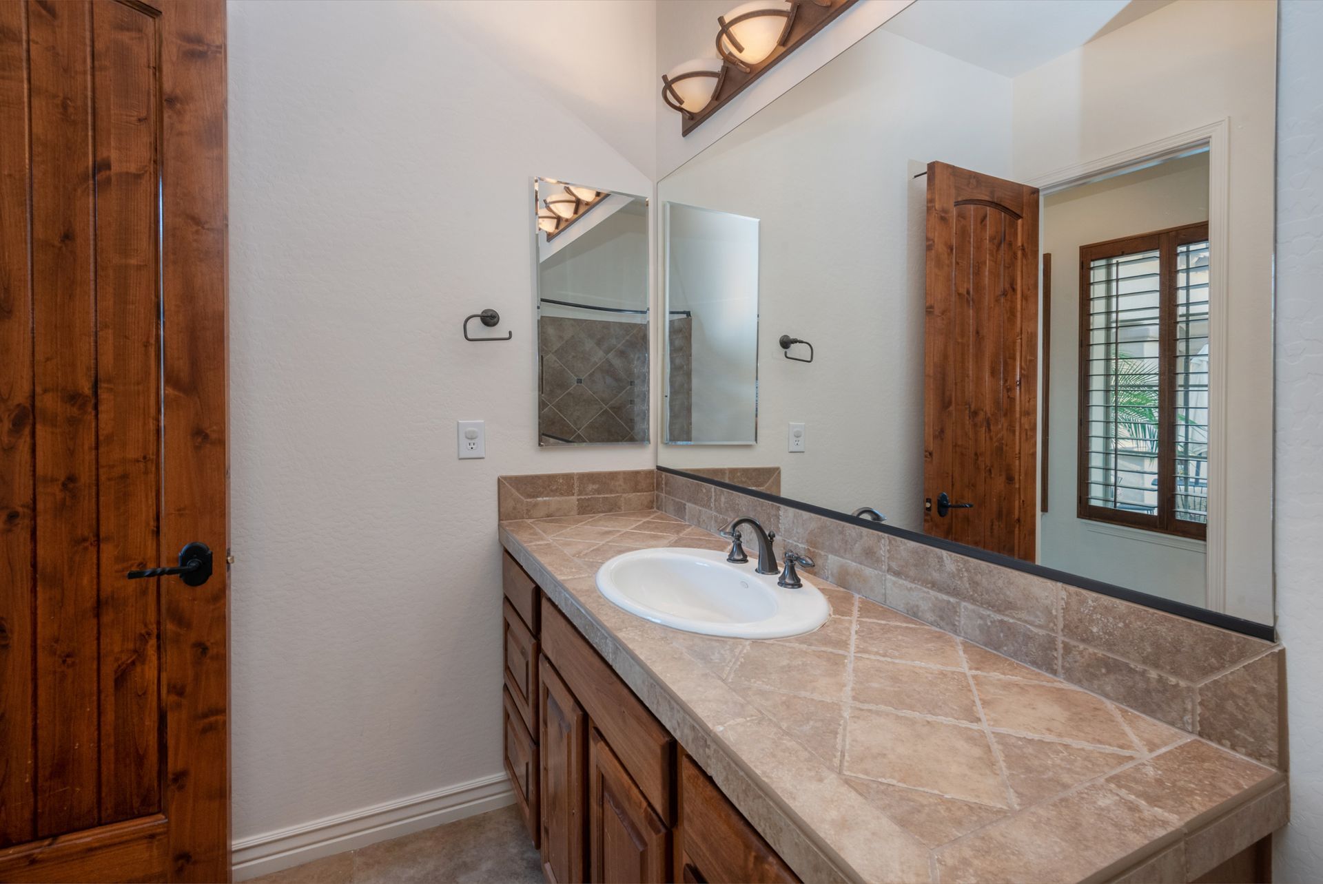 A bathroom with a sink , mirror and wooden cabinets.
