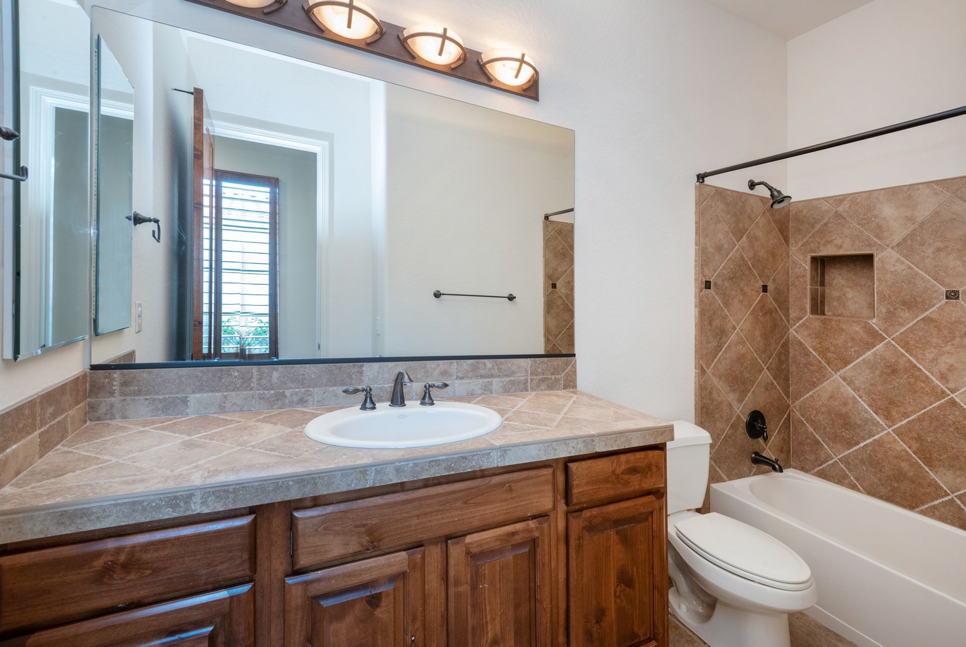 A bathroom with a sink , toilet , bathtub and mirror.