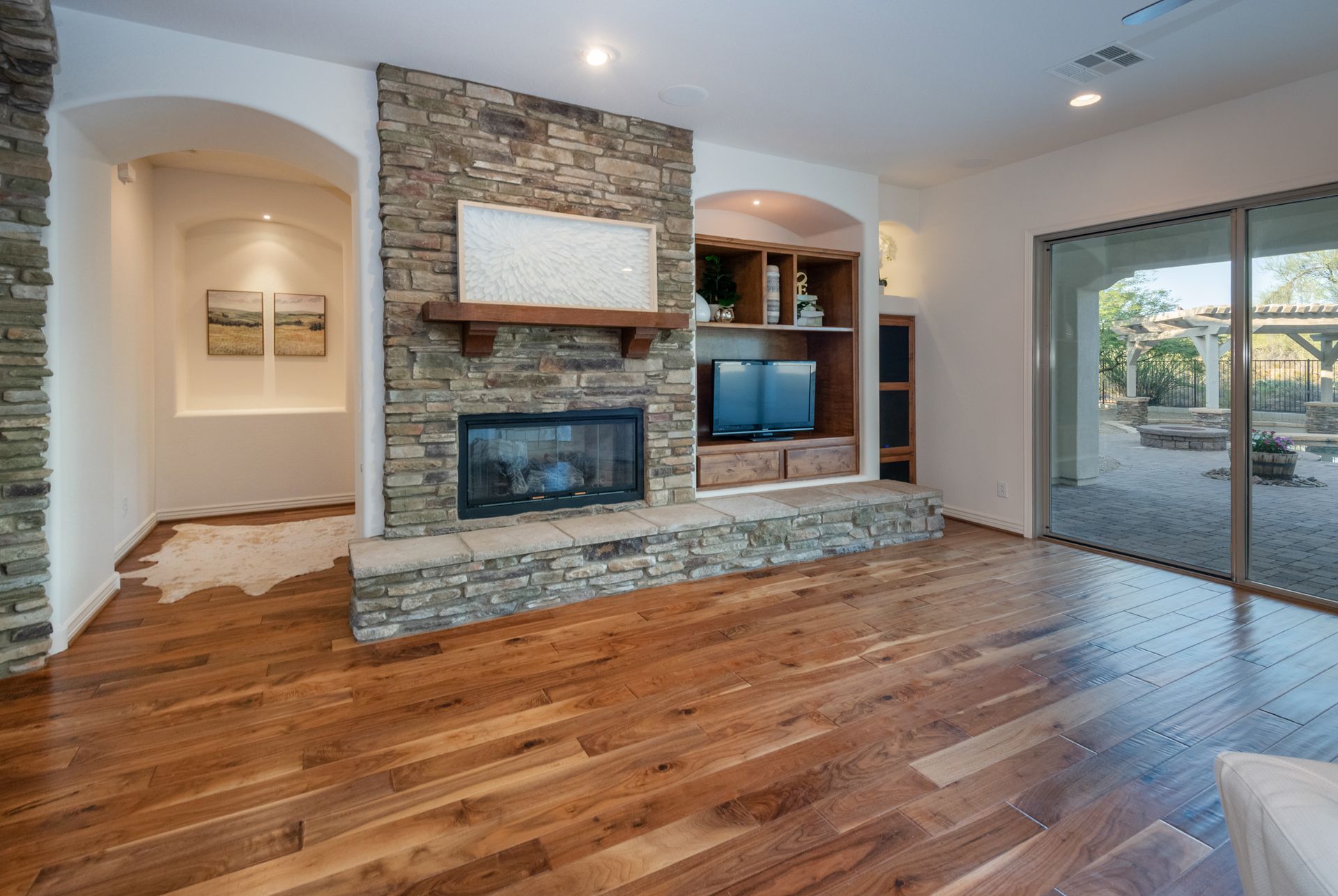 A living room with hardwood floors and a stone fireplace