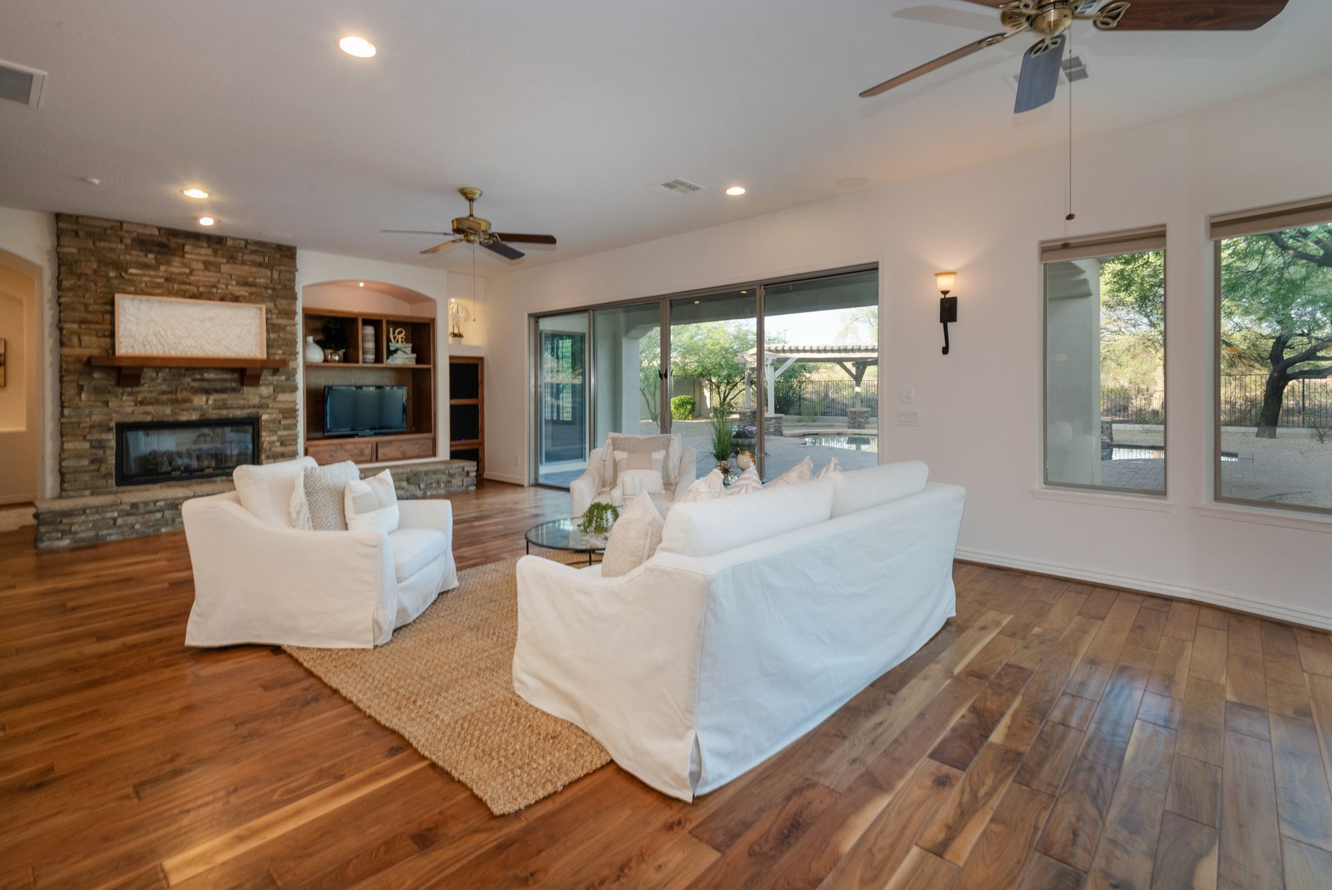 A living room with a couch , chairs , a fireplace and a ceiling fan.