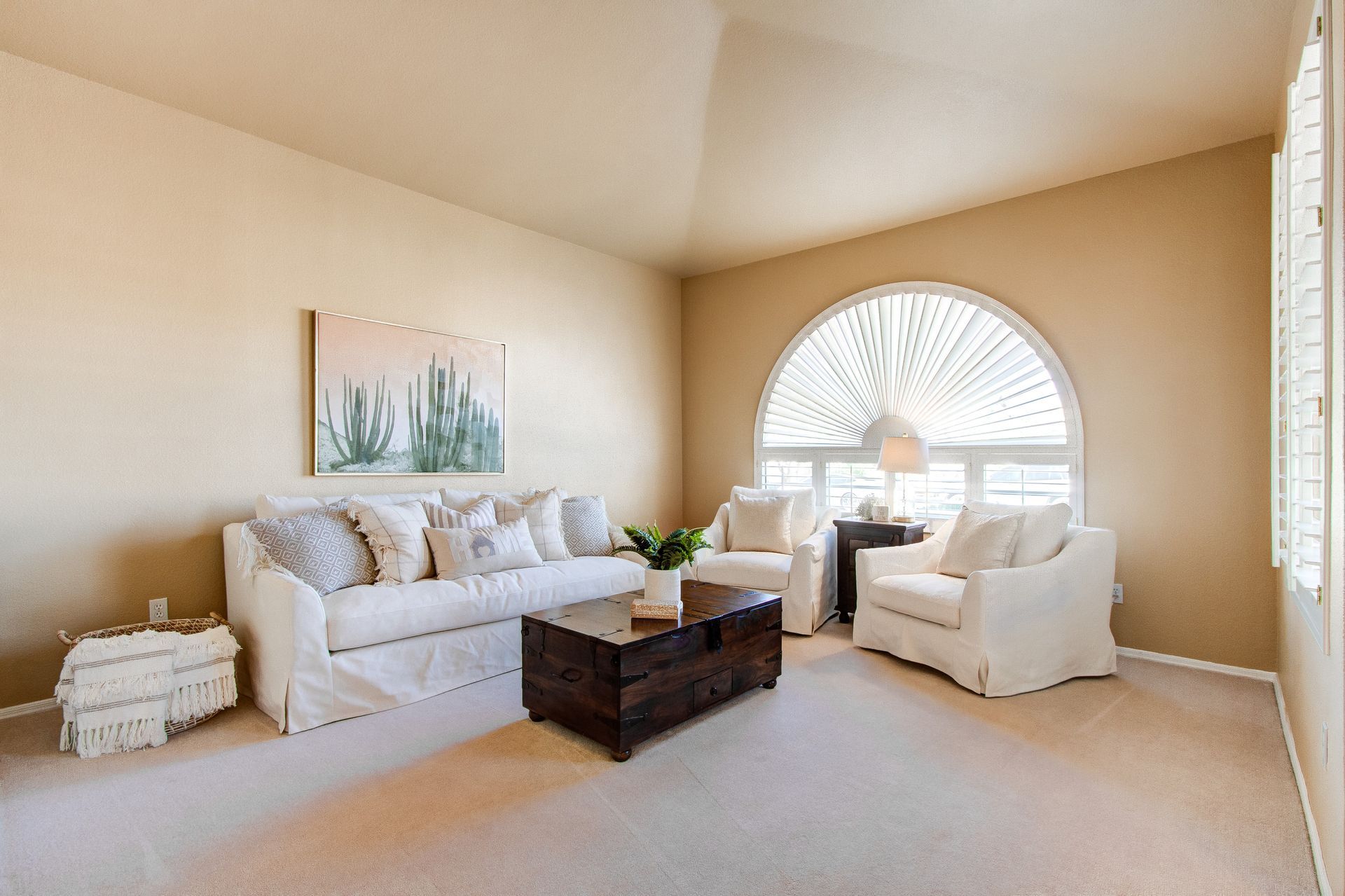 A living room with a couch , two chairs , a coffee table and a large window.