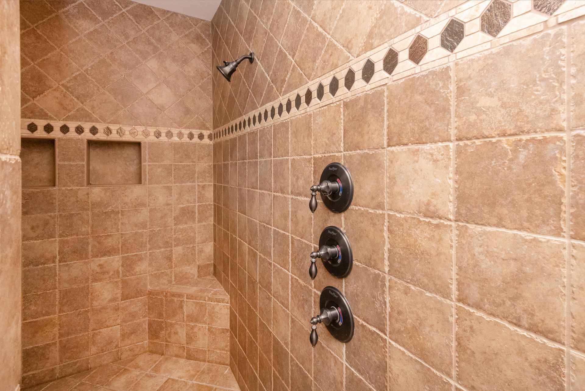A bathroom with a walk in shower and three shower heads.