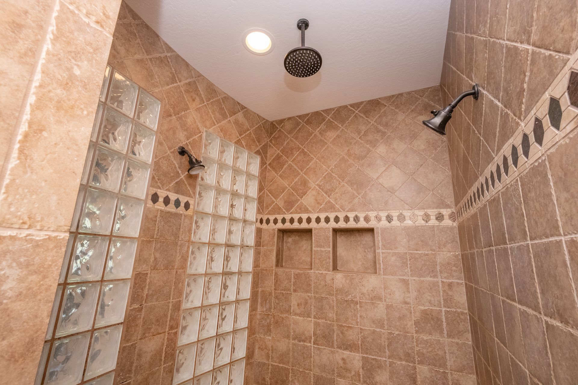 A bathroom with a walk in shower and a glass block wall.