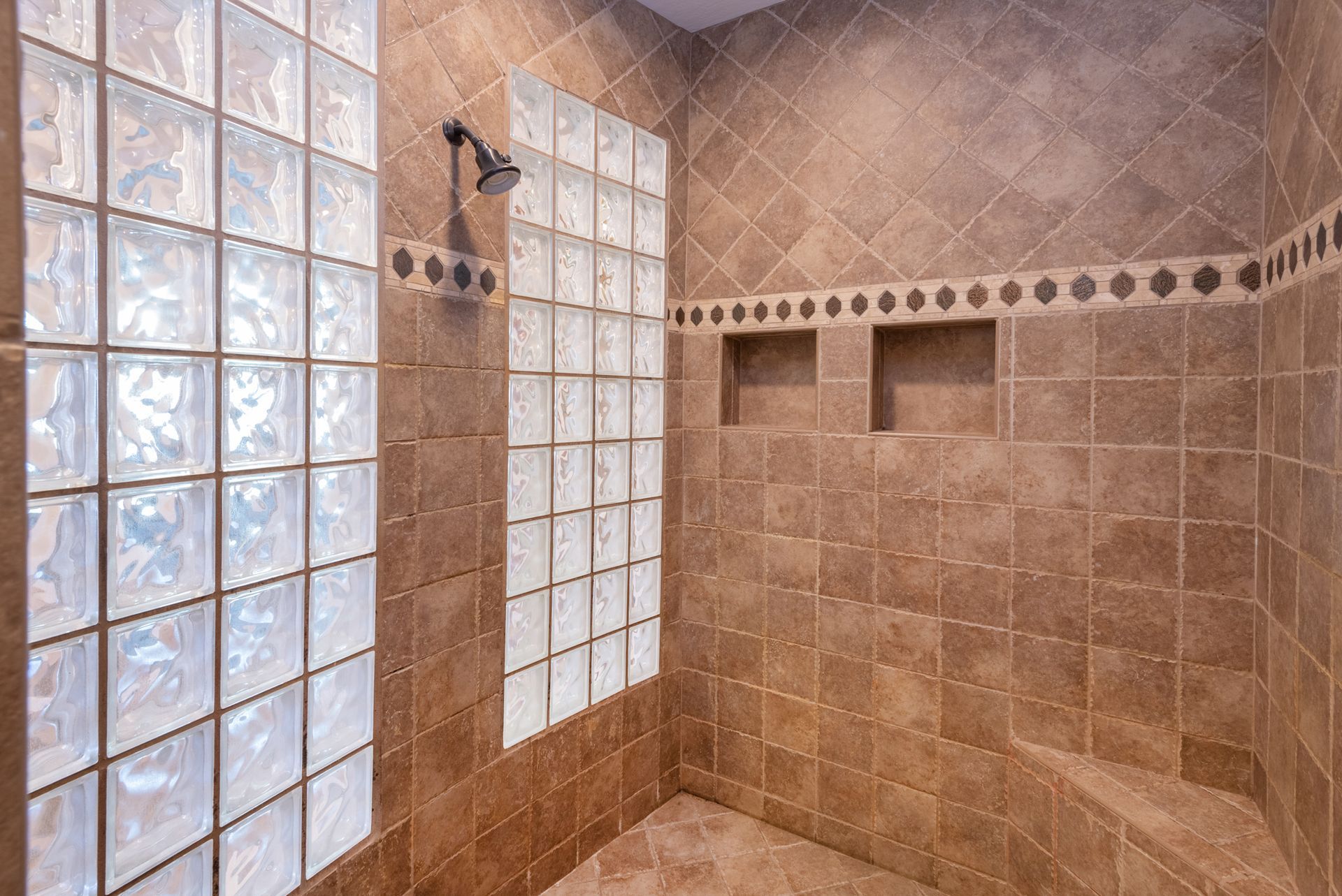 A bathroom with a walk in shower and a glass block wall.