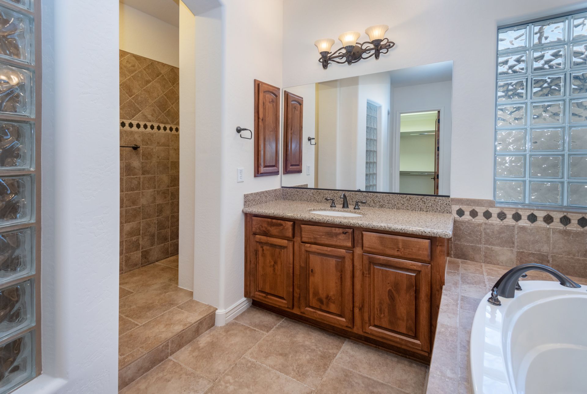 A bathroom with a tub , sink , mirror and walk in shower.