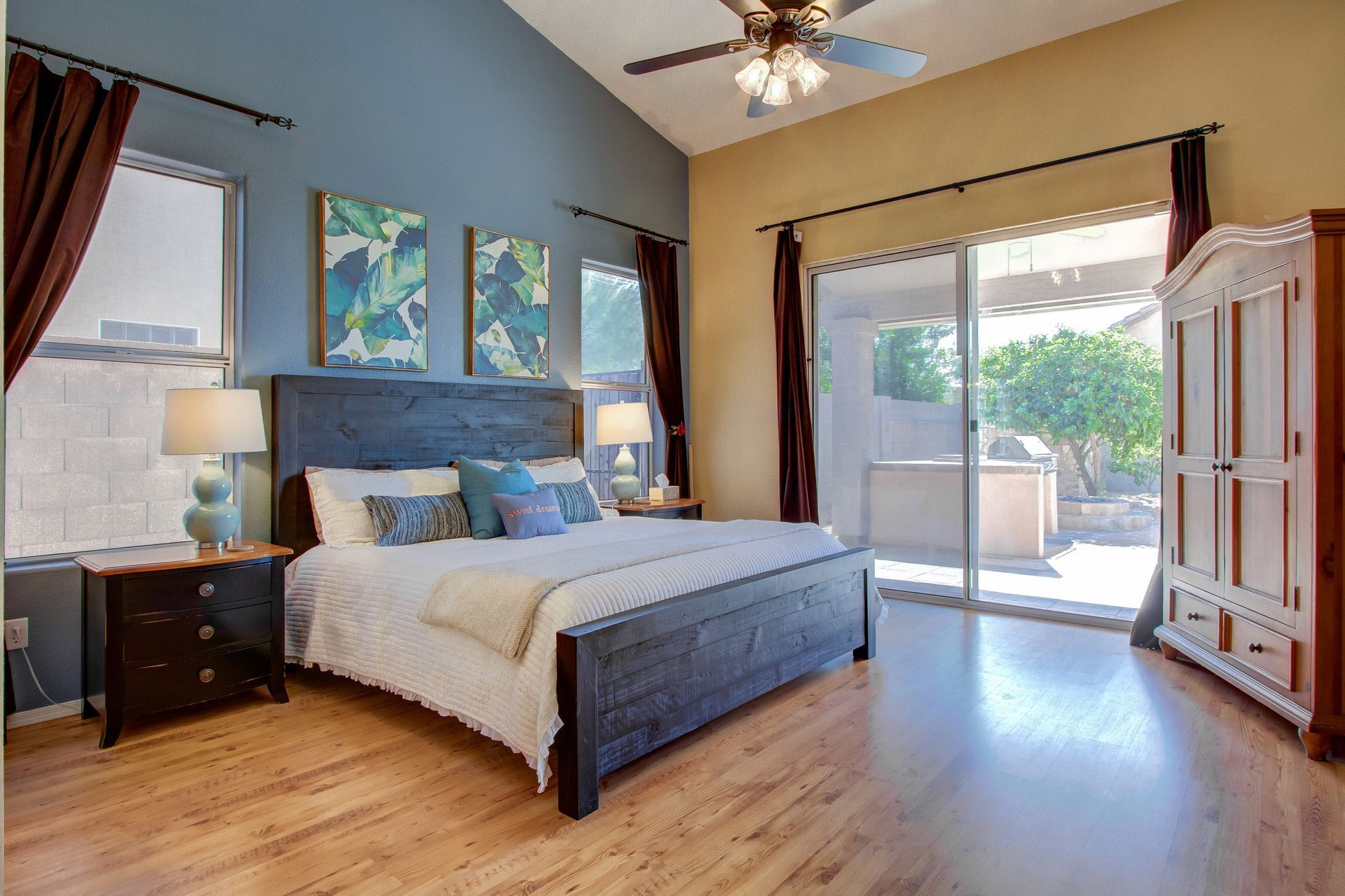 A bedroom with a bed , nightstands , a ceiling fan and a sliding glass door.