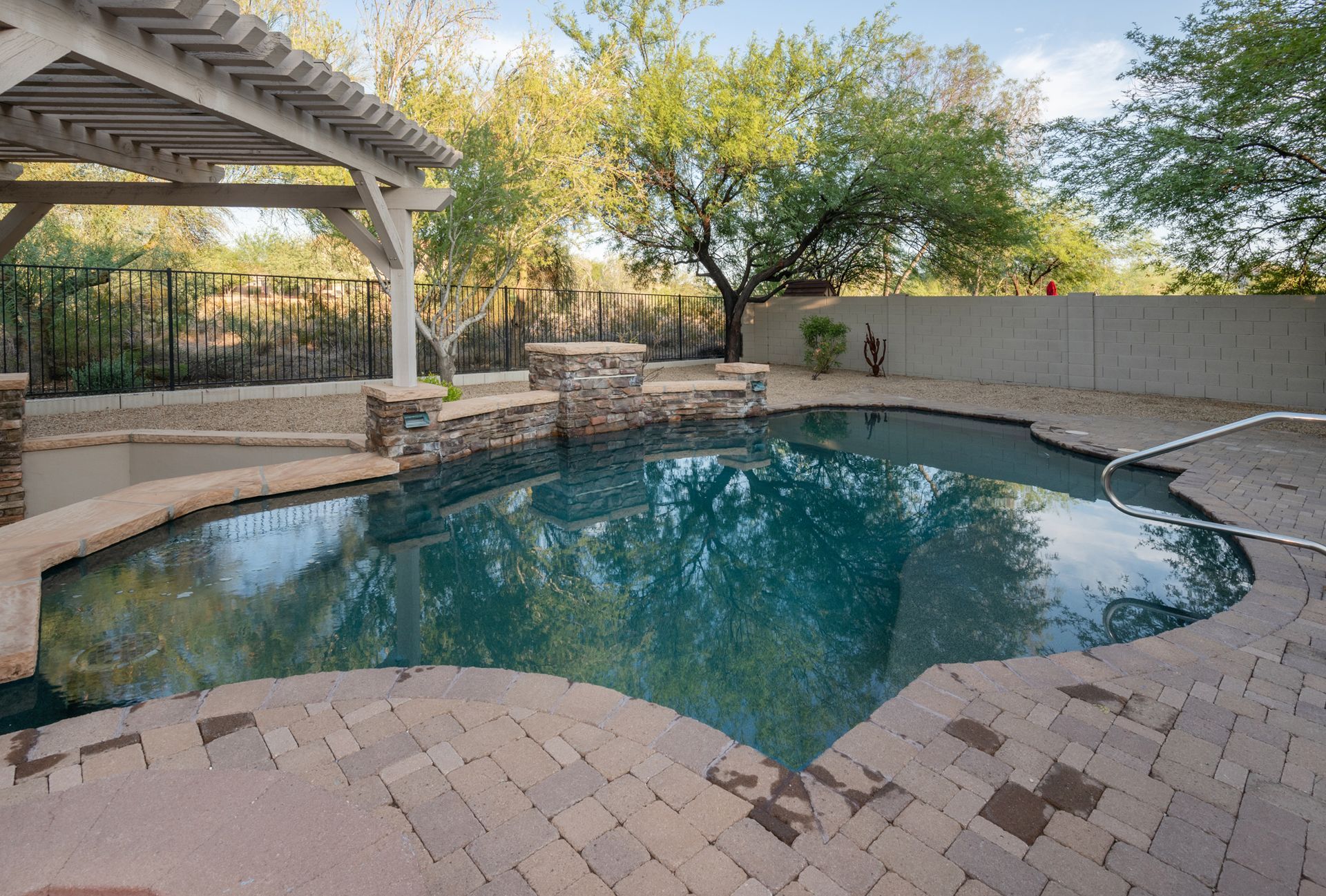 A large swimming pool with a pergola in the backyard