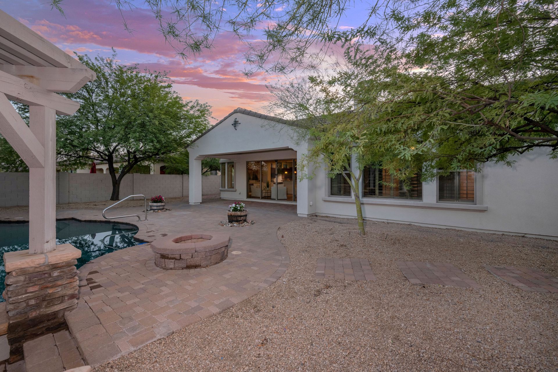 A white house with a swimming pool and a fire pit in the backyard.