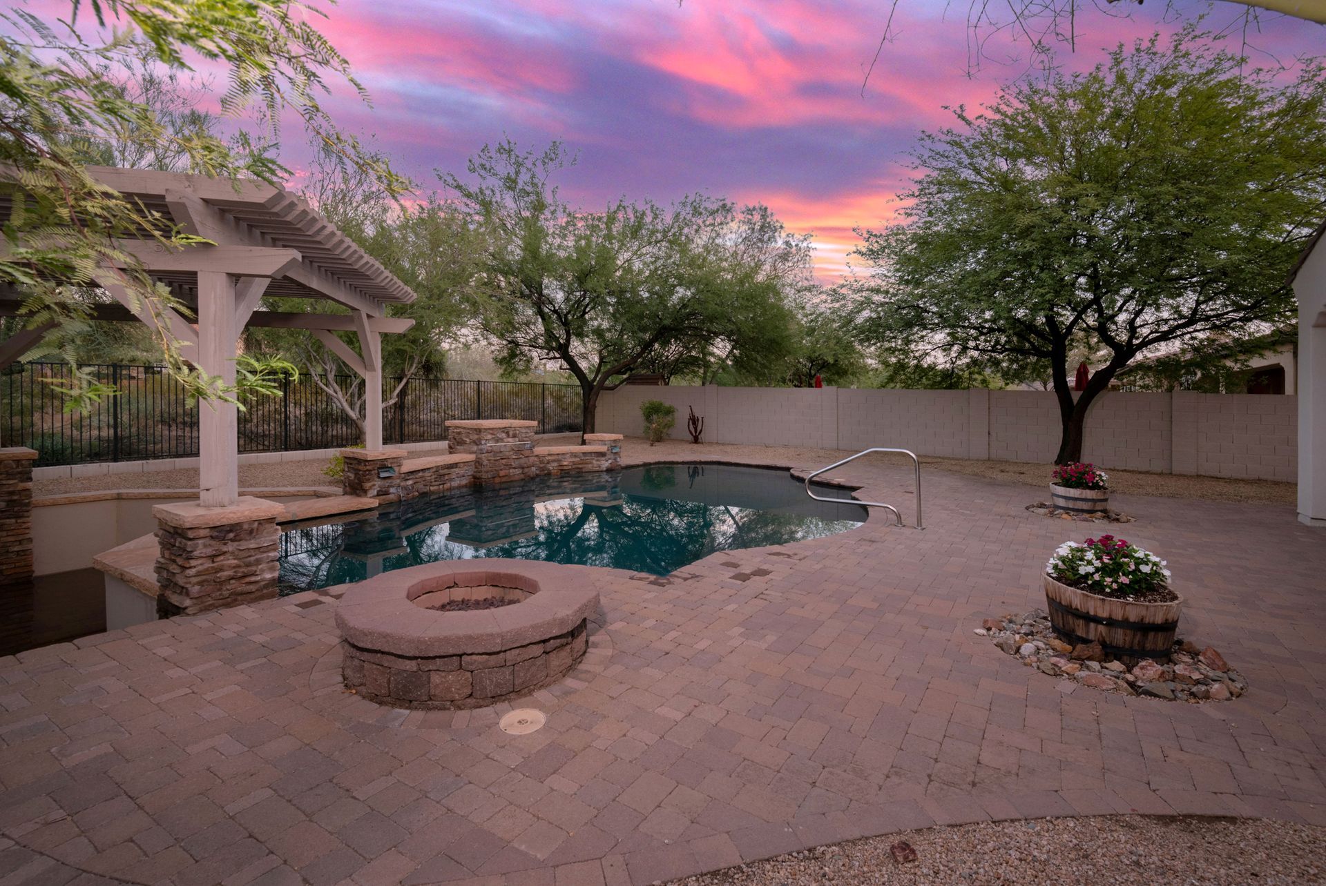 A large swimming pool with a fire pit in the backyard at sunset.
