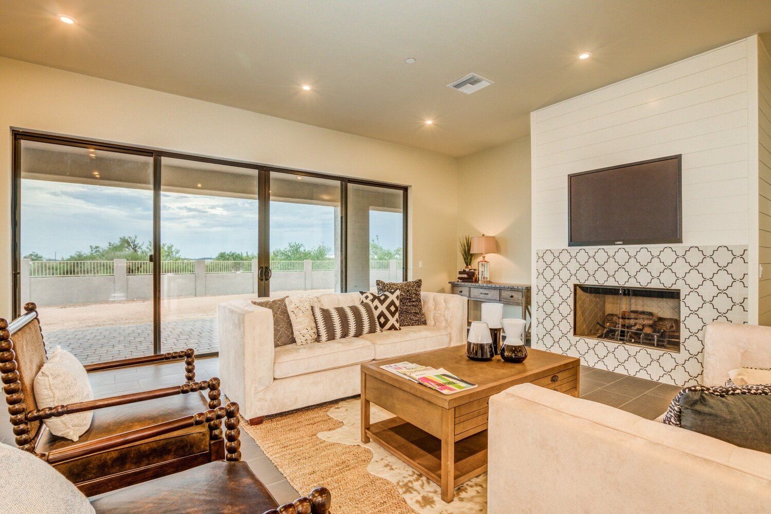 A living room with a couch , chair , coffee table , fireplace and television.