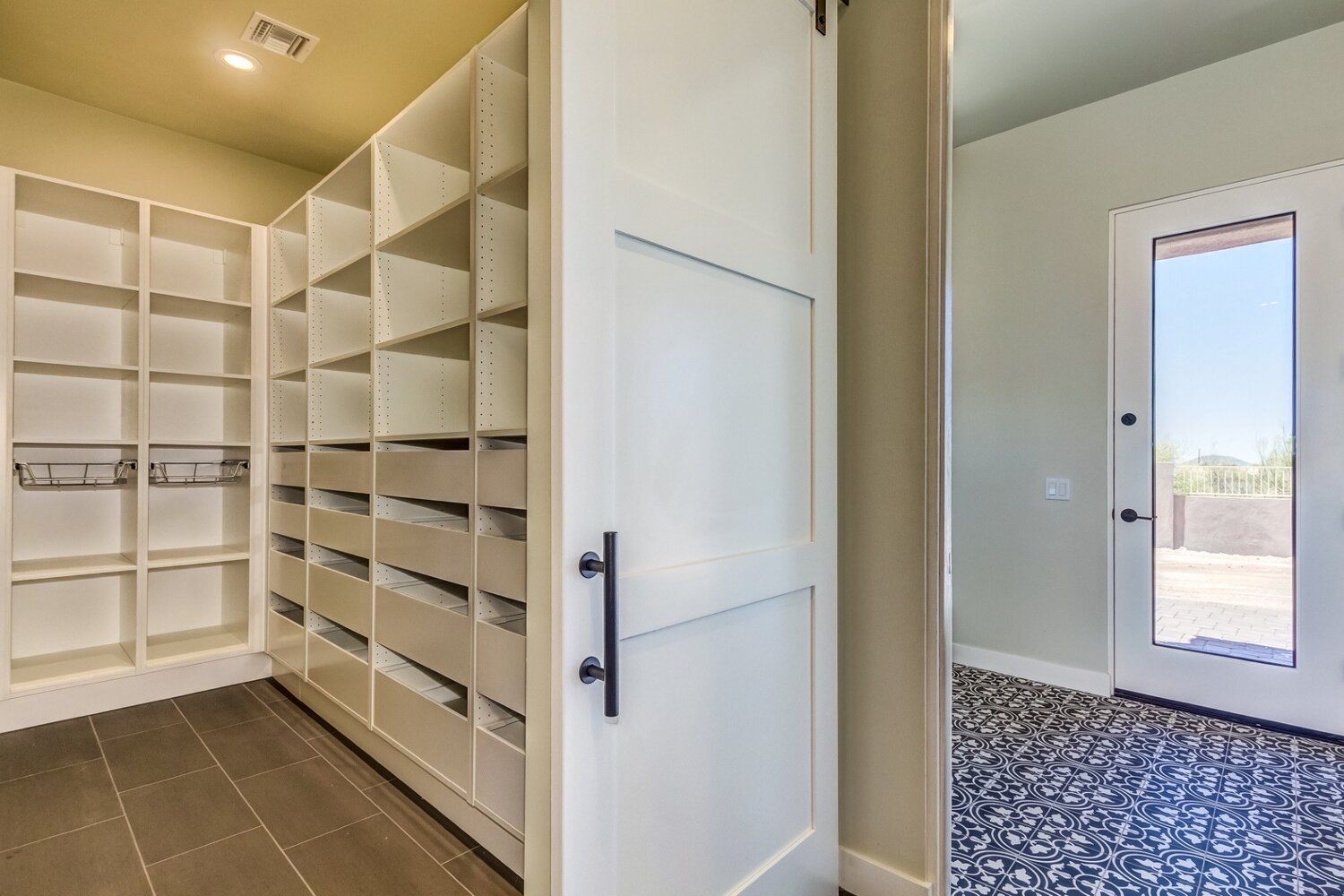 A walk in closet with lots of shelves and drawers next to a door.