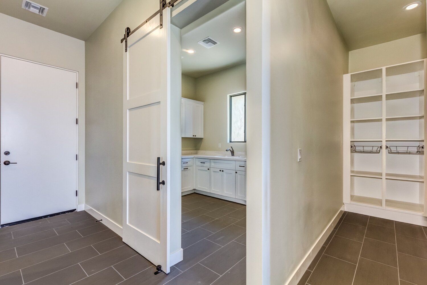 A hallway with a sliding barn door leading to a laundry room.