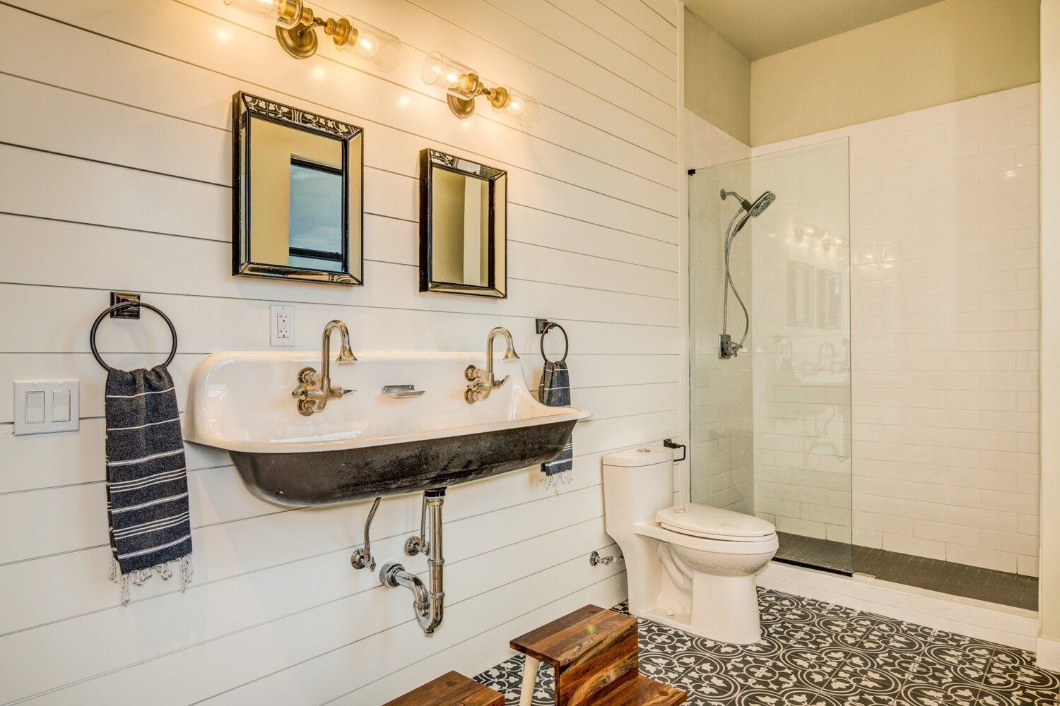 A bathroom with a sink , toilet , mirrors and a walk in shower.