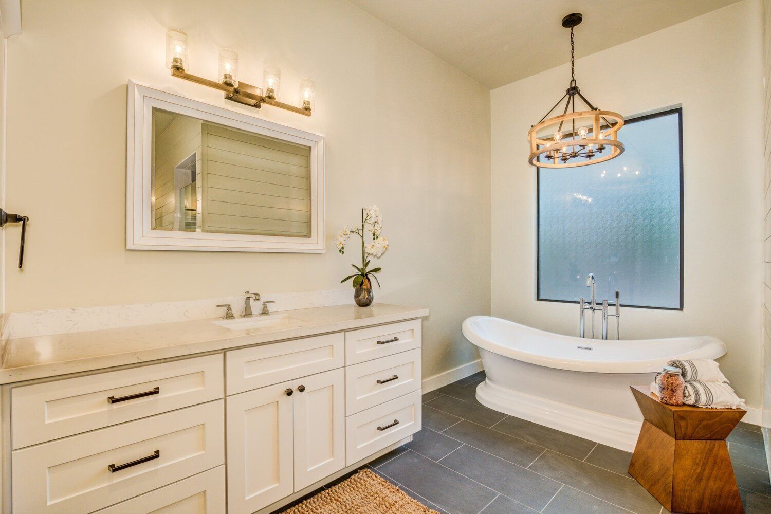 A bathroom with a tub , sink , mirror and window.