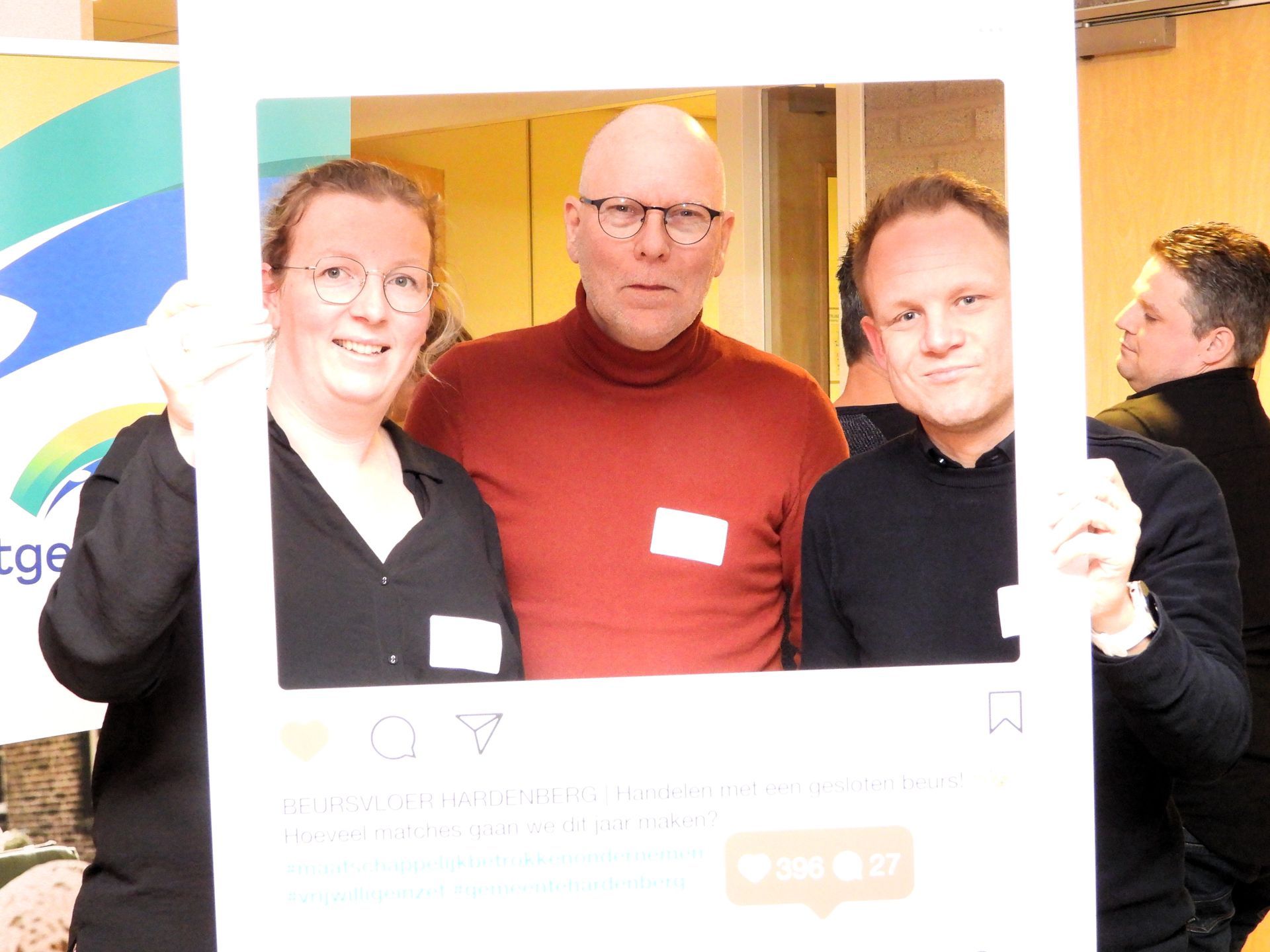 Drie mensen poseren in een wit Instagram-frame. Ze zijn binnen en lachen.