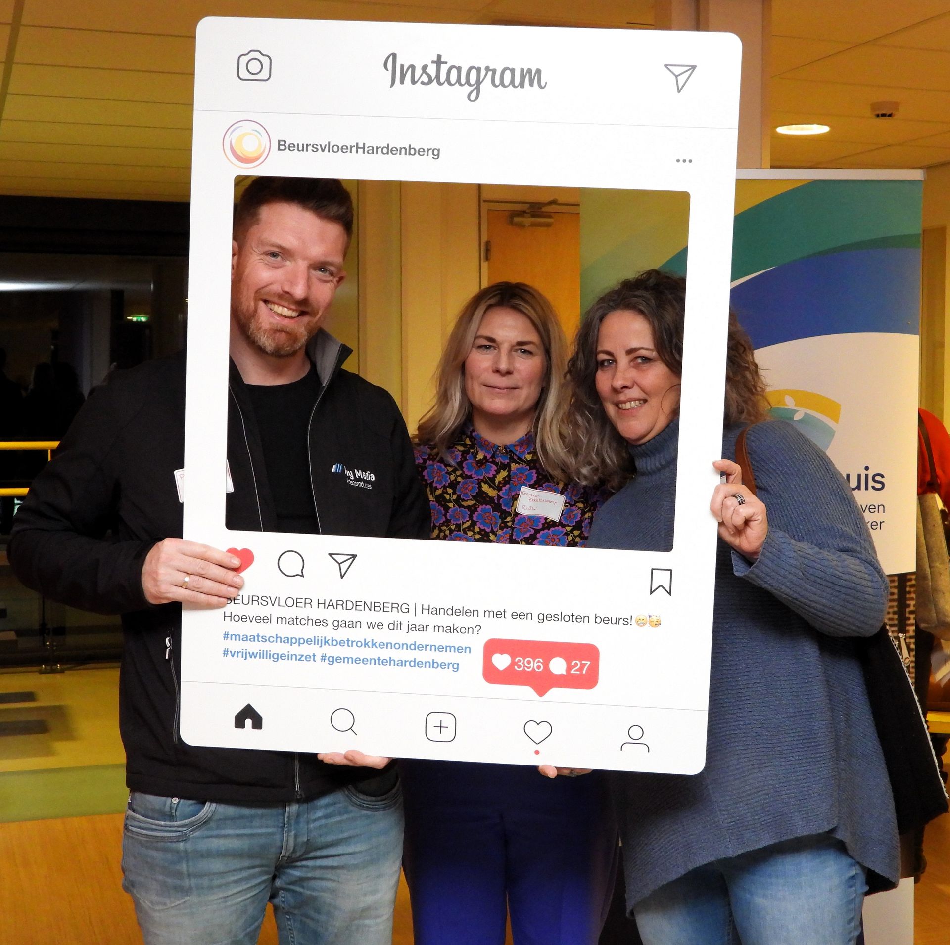 Drie mensen poseren in een fotolijst met Instagram-thema tijdens een evenement.