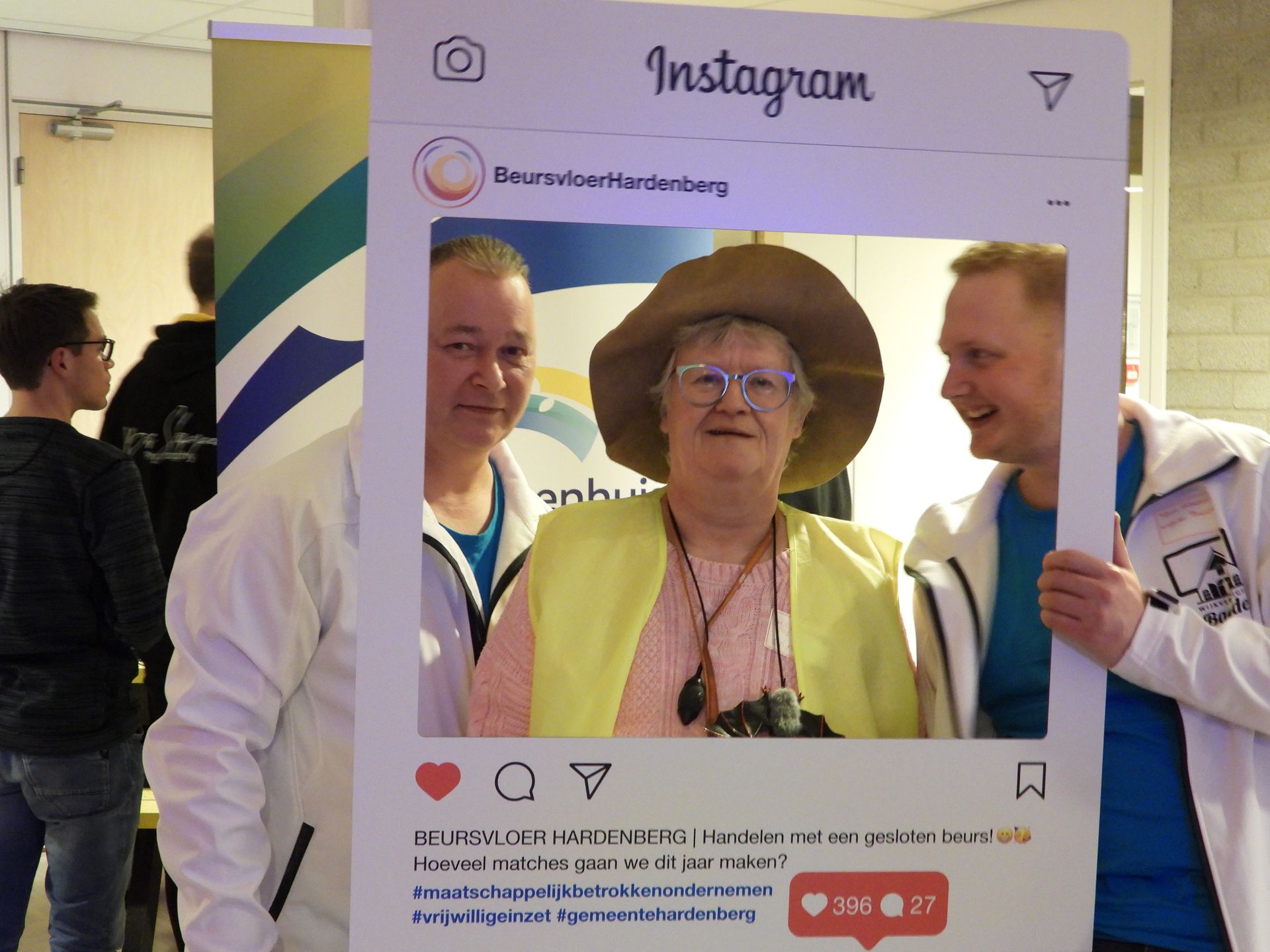 Drie mensen poseren in een groot Instagram-kader. Twee mannen staan ​​aan weerszijden van een vrouw die een hoed en een bril draagt.