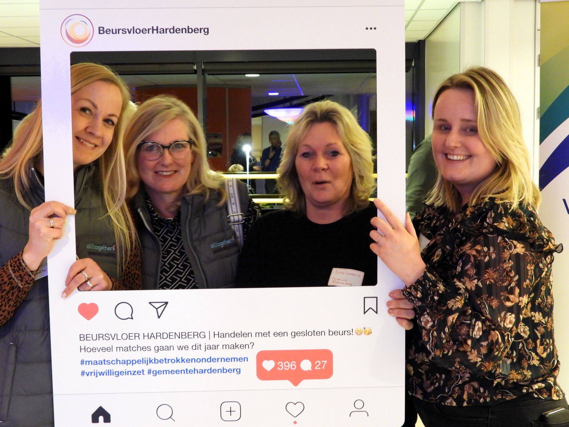 Vier vrouwen lachend poseren ze met een grote Instagram-fotolijst op een evenement.
