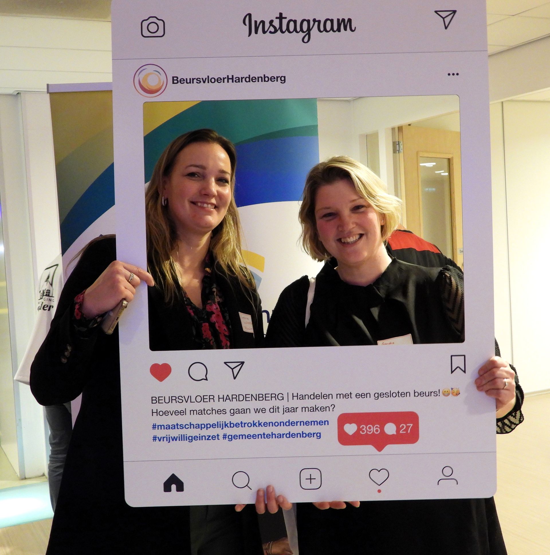 Twee lachende vrouwen poseren met een grote Instagram-fotolijst.