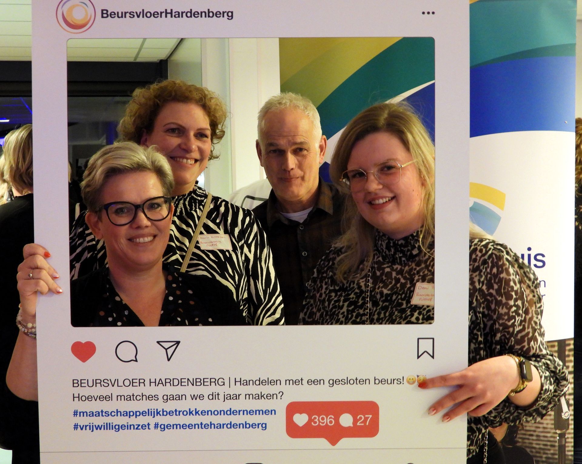 Een groep van vier mensen poseert achter een Instagram-frame tijdens een evenement.
