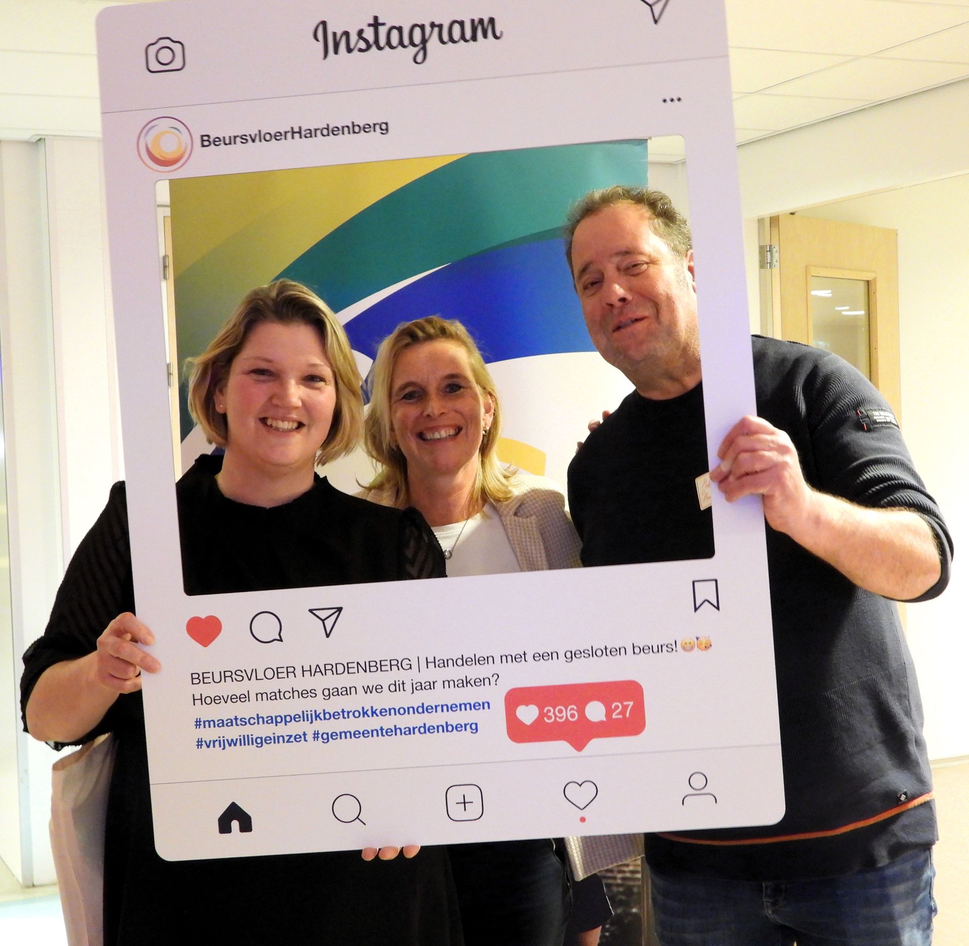 Drie mensen poseren in een groot Instagram-kader. Twee vrouwen en een man glimlachen.
