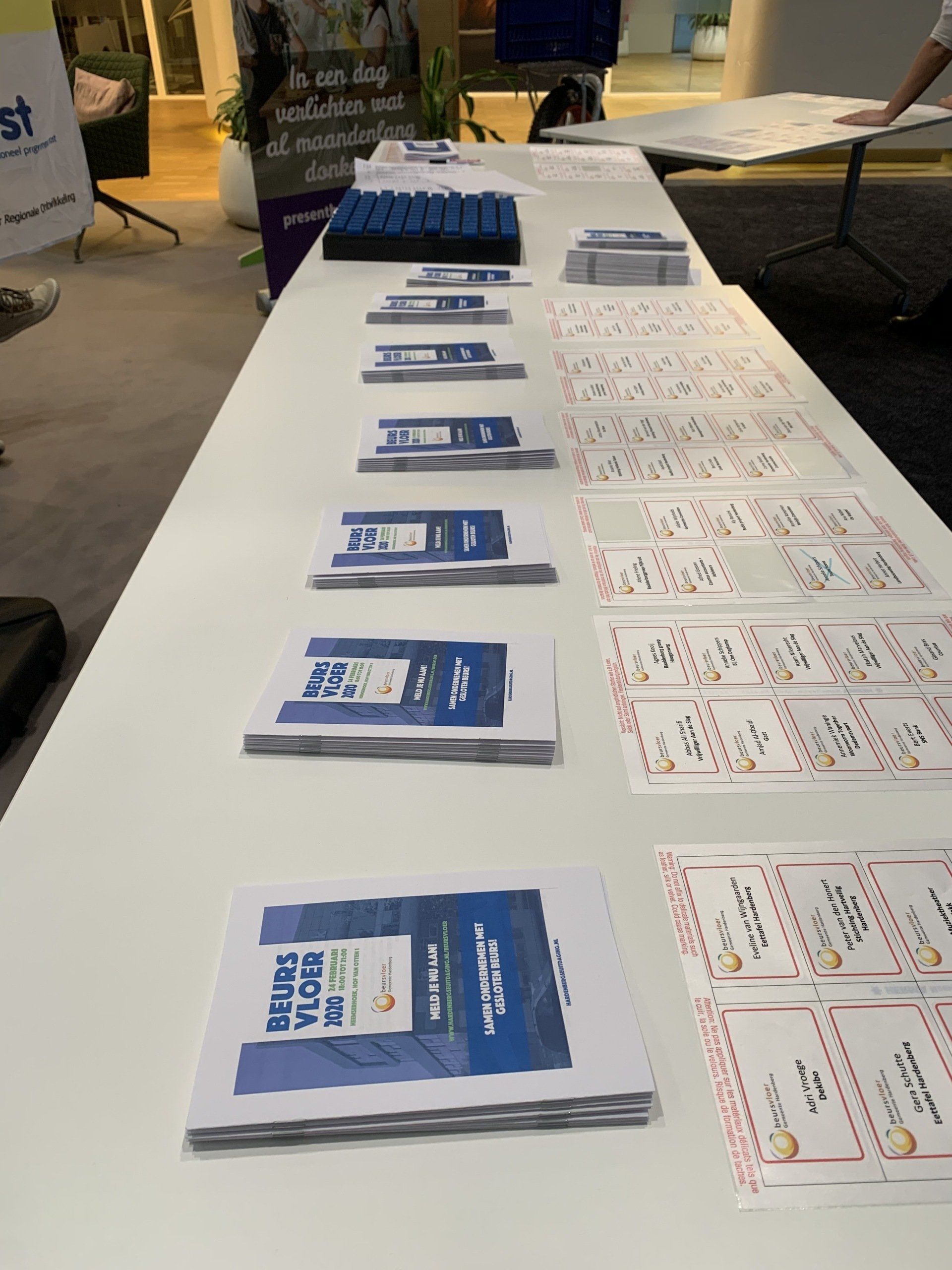 Een tafel met stapels informatiefolders en indexkaarten op een evenement.