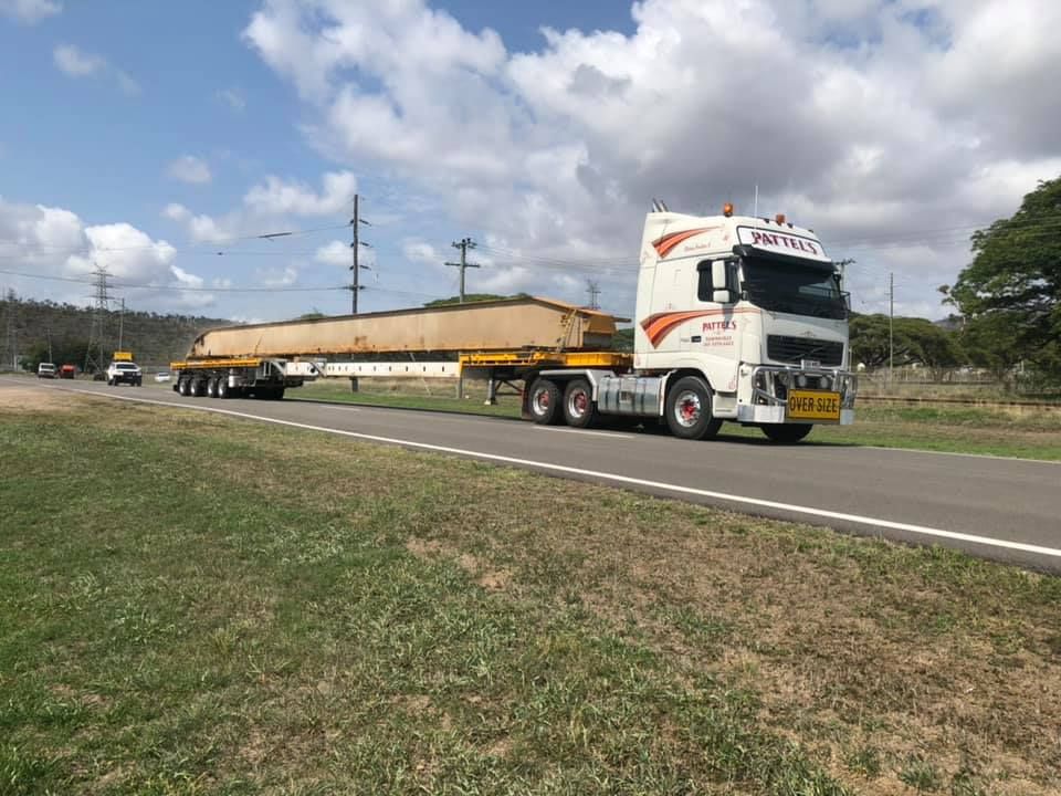 A Large Semi Truck Is Driving Down A Road Next To A Grassy Field — Pattel's Heavy Haulage Townsville Pty Ltd In Garbutt, QLD