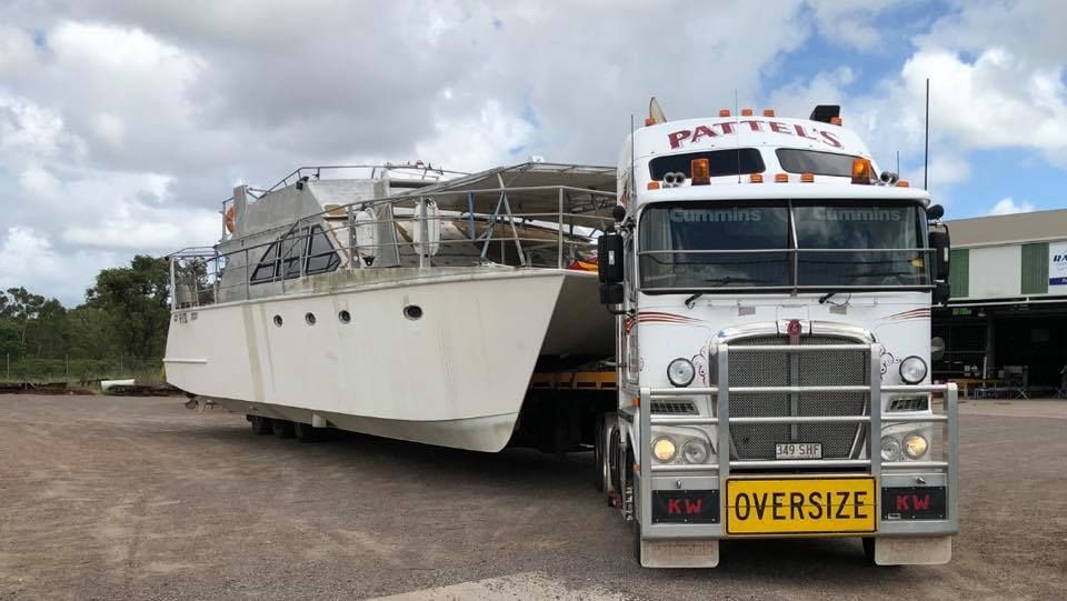 A Large White Boat Is Being Transported By An Oversized Truck — Pattel's Heavy Haulage Townsville Pty Ltd In Garbutt, QLD