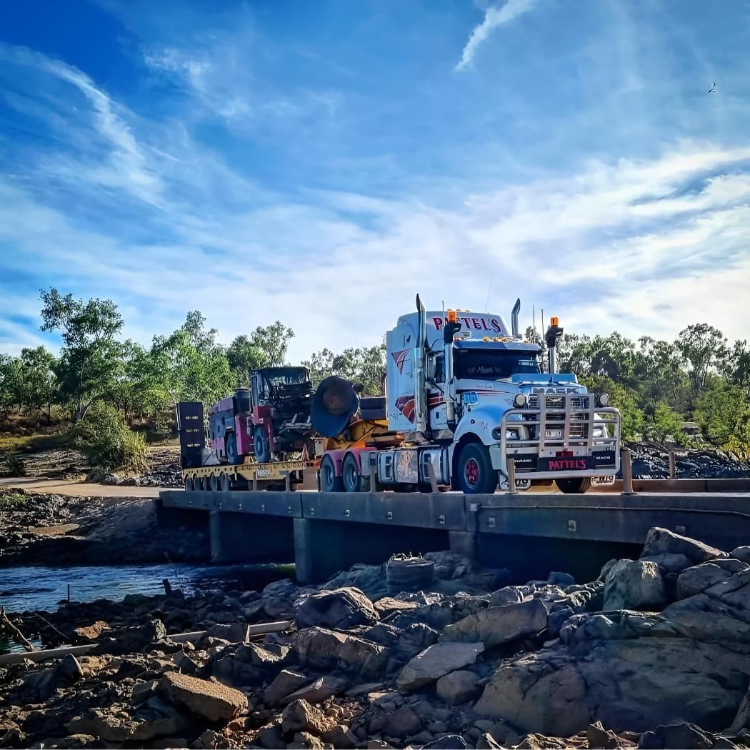 A Large White Truck Is Crossing A Bridge Over A River — Pattel's Heavy Haulage Townsville Pty Ltd In Garbutt, QLD