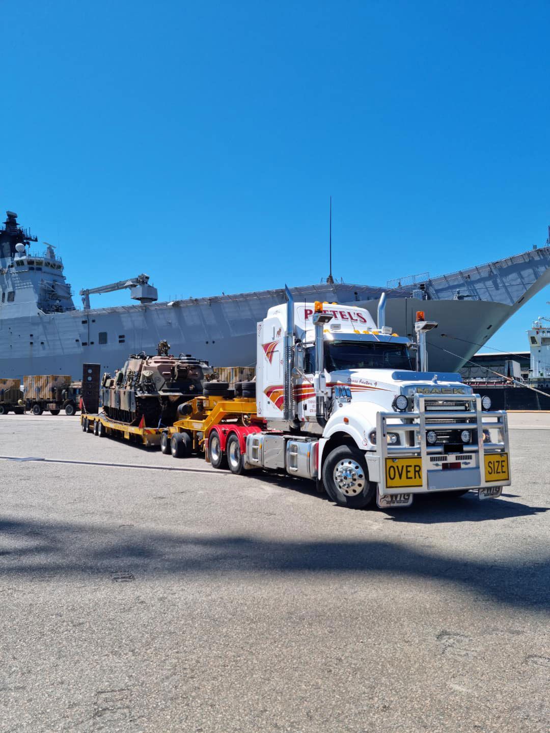 A Semi Truck Is Parked In Front Of A Large Ship — Pattel's Heavy Haulage Townsville Pty Ltd In Garbutt, QLD