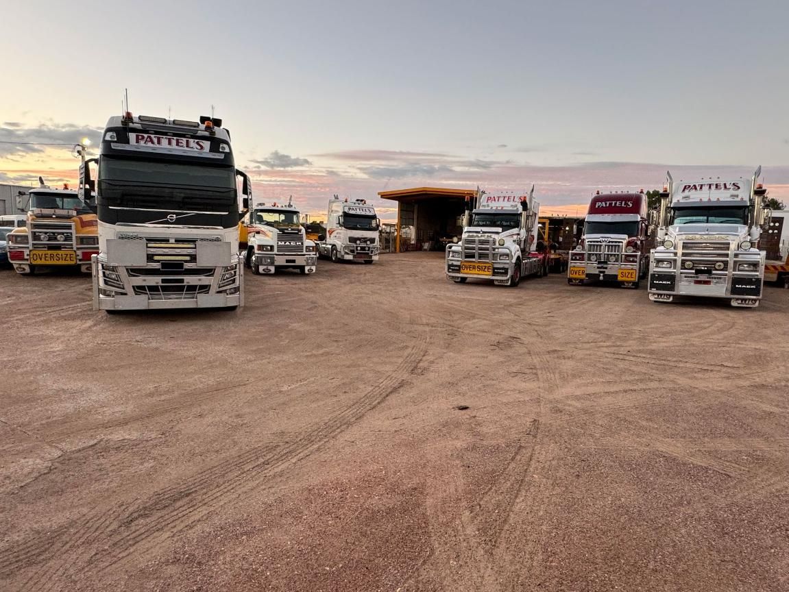 A Row Of Trucks Are Parked In A Dirt Lot — Pattel's Heavy Haulage Townsville Pty Ltd In Garbutt, QLD