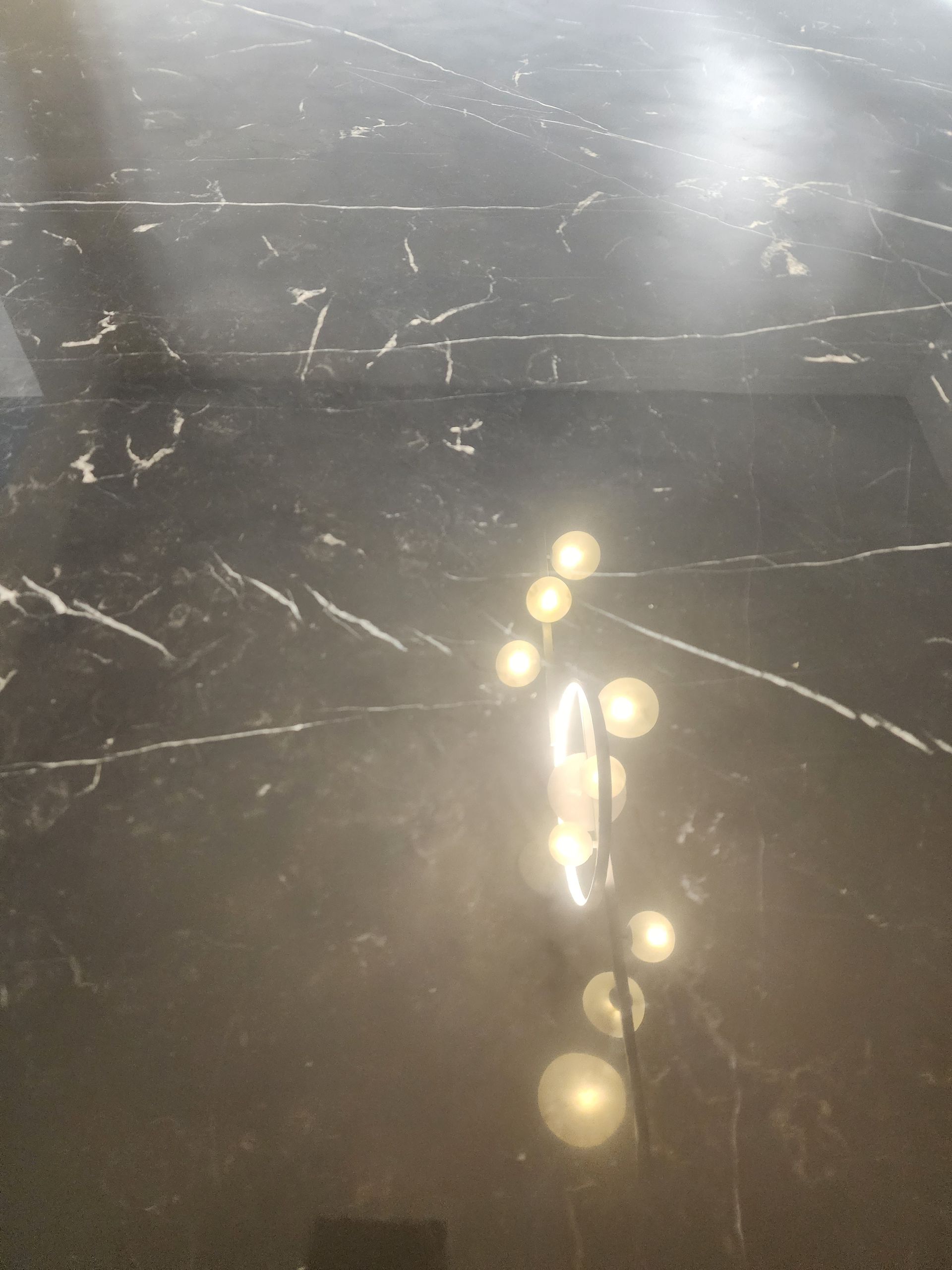 Reflective dark marble surface with bright light glare and white veining.