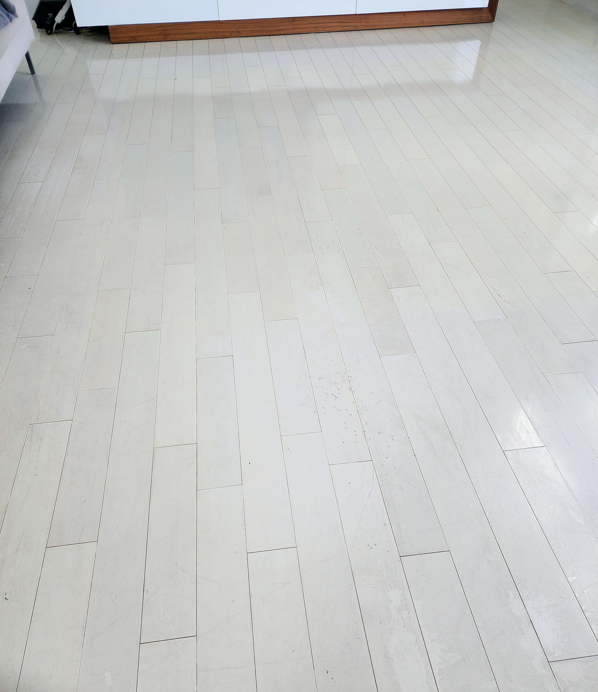 White speckled floor with a wooden baseboard along the back wall