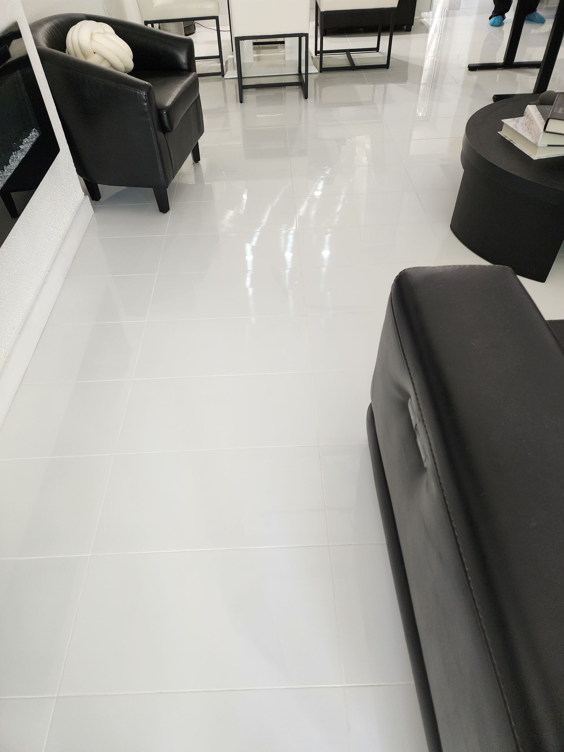 Modern living room with black chairs and a white glossy tiled floor